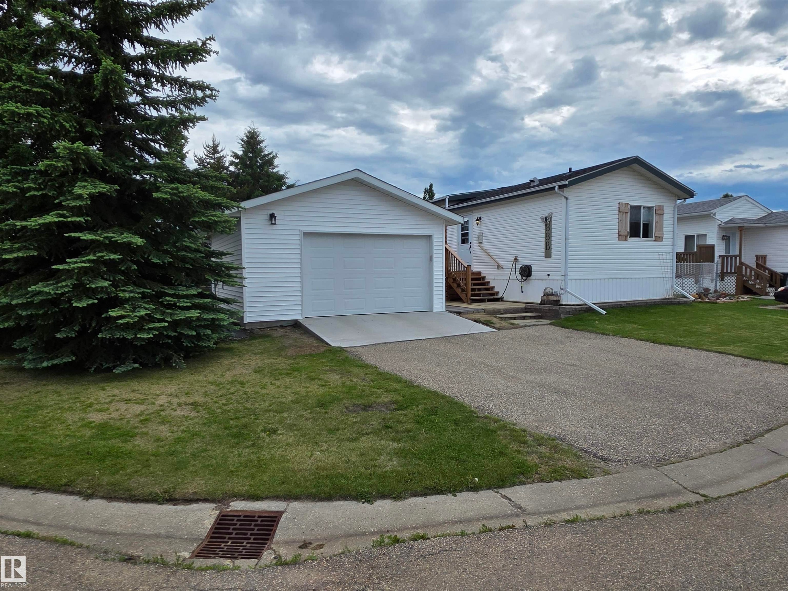 Detached garage with white vinyl siding, concrete driveway apron, and gravel parking pad - 88B 3400 48 Street, Stony Plain, AB