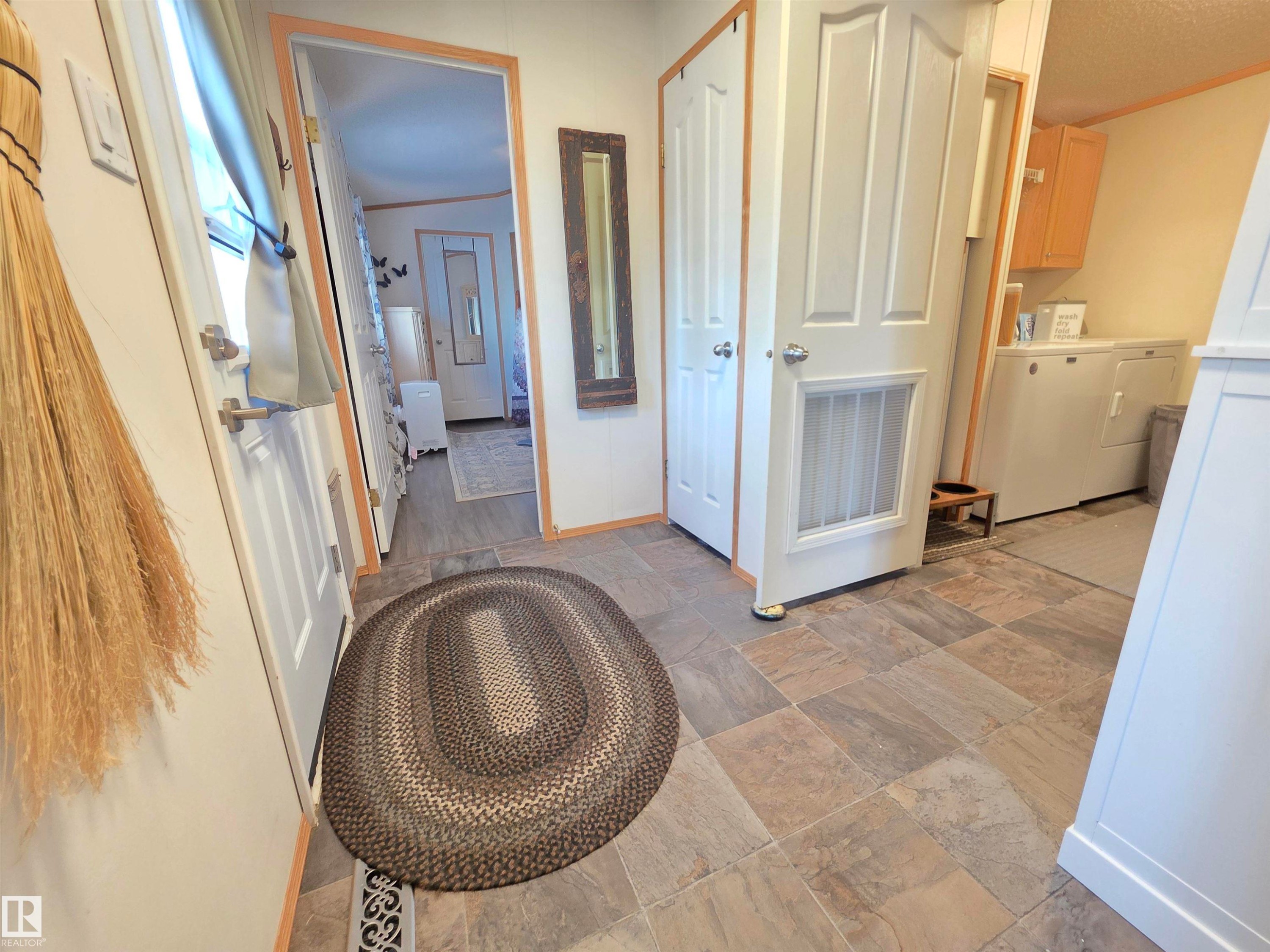 Entry area featuring tile flooring, white paneled doors, and natural wood trim - 88B 3400 48 Street, Stony Plain, AB