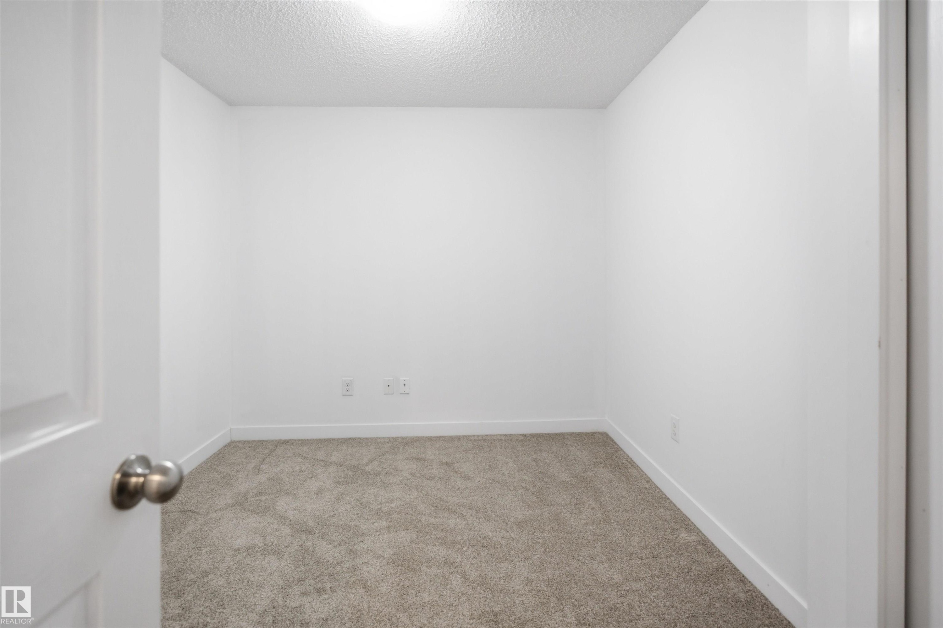 Bright room featuring plush neutral-toned carpeting, white walls, and a ceiling-mounted light fixture - 115 274 Mcconachie Drive, Edmonton, AB