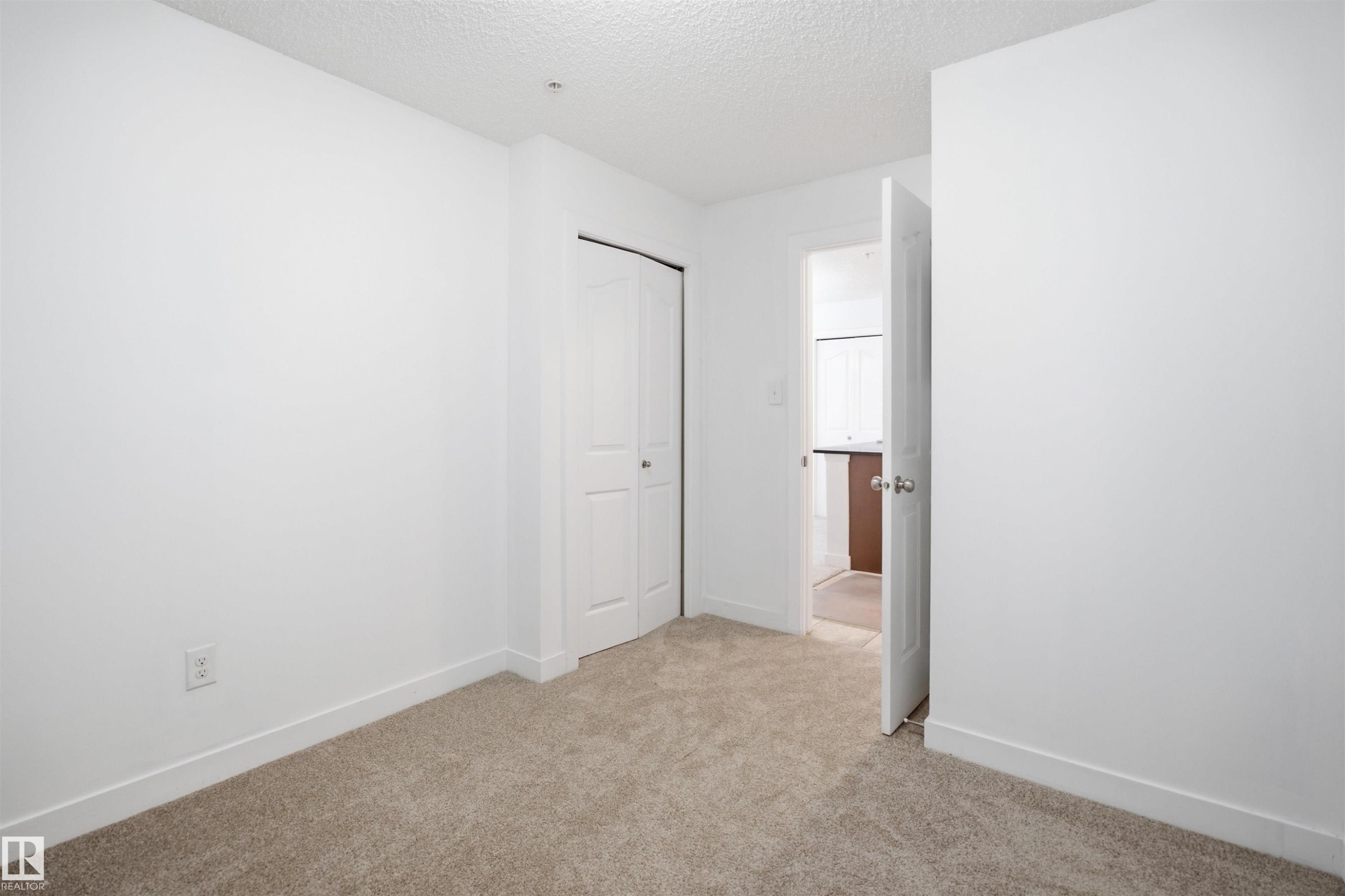 Carpeted room with white walls, white baseboards, and a bi-fold closet door - 115 274 Mcconachie Drive, Edmonton, AB