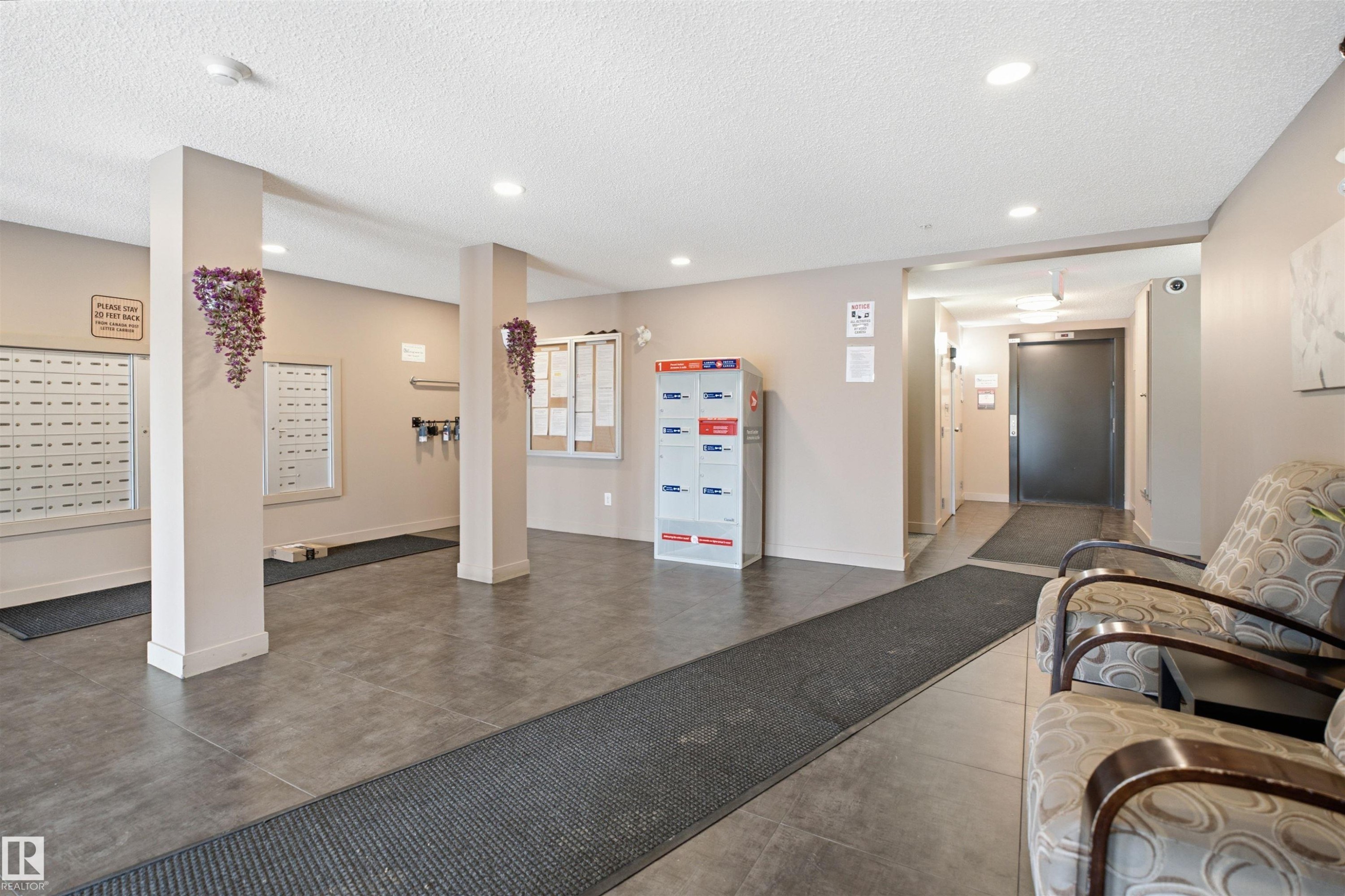 Building lobby featuring grey tile flooring, recessed ceiling lighting, and a mail area with individual boxes and parcel lockers - 115 274 Mcconachie Drive, Edmonton, AB