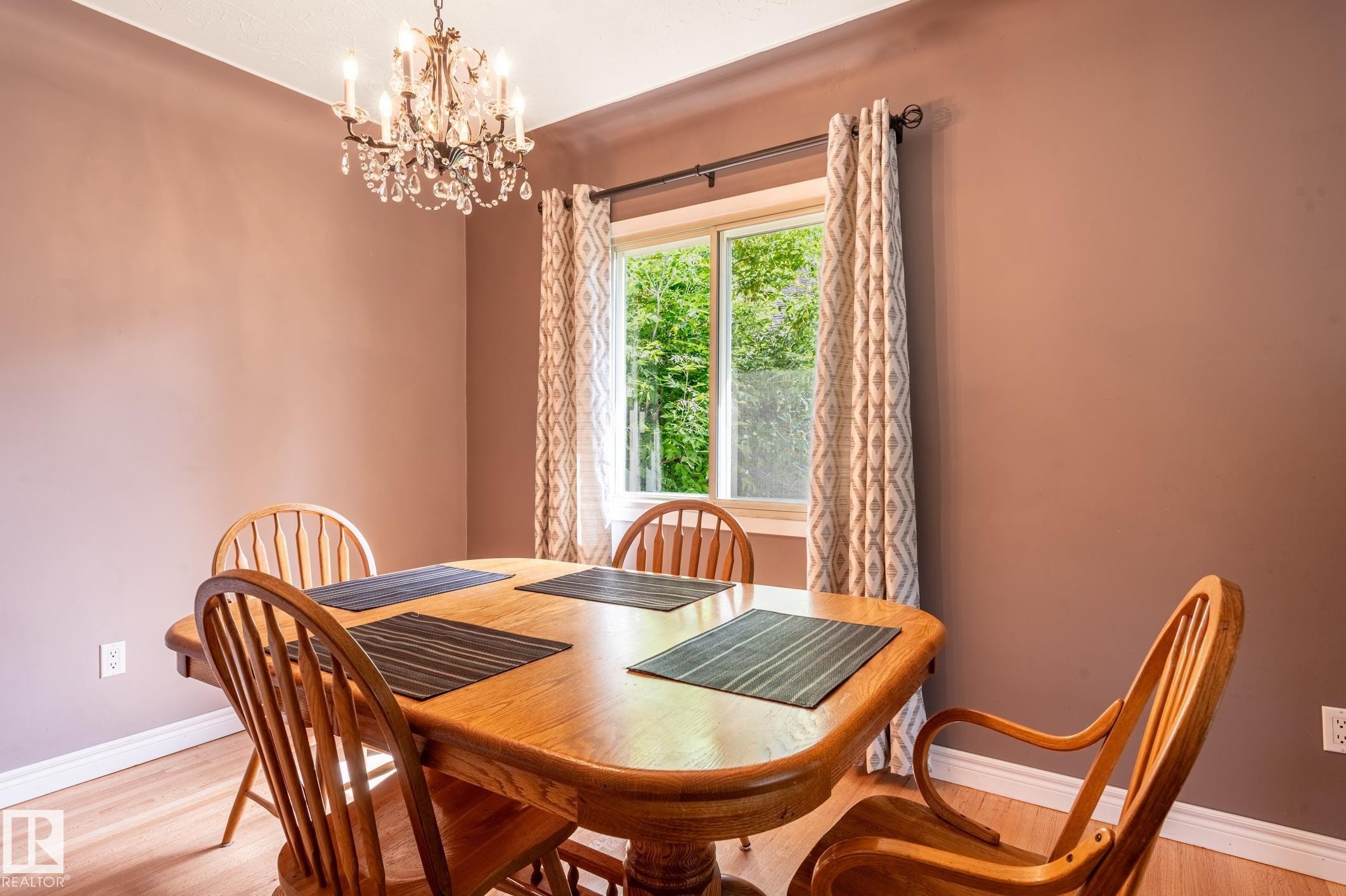 Dining area featuring wood-finish flooring, a crystal chandelier, and a window with natural light - 14708 108 Av, Edmonton, AB