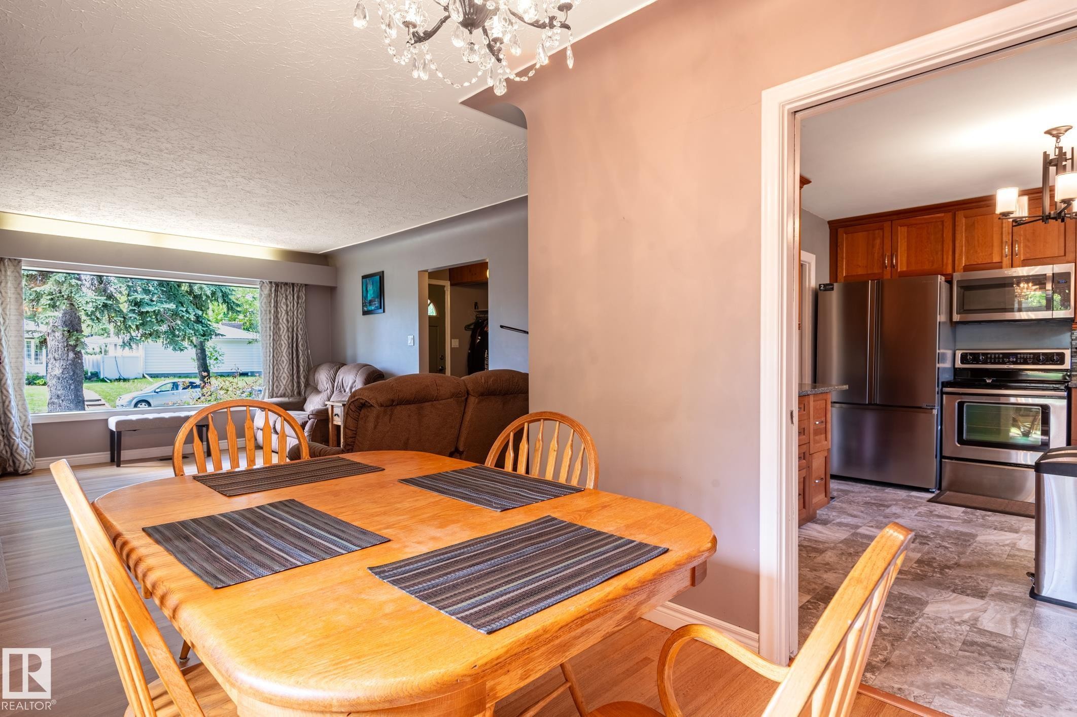 Dining area featuring wood-finish flooring and a crystal chandelier - 14708 108 Av, Edmonton, AB