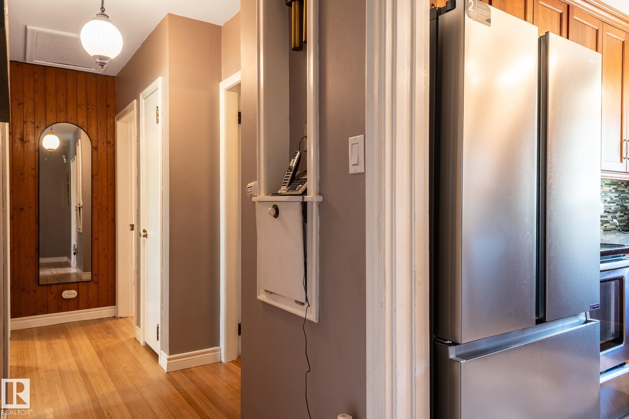 Hallway featuring wood-finish flooring and a wood panel accent wall - 14708 108 Av, Edmonton, AB