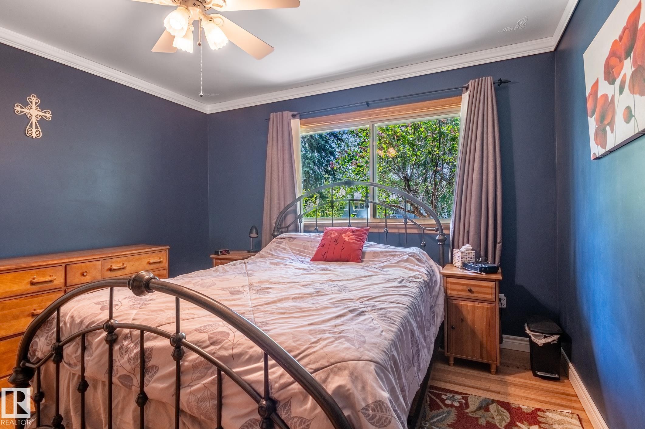 Bedroom featuring wood-finish flooring, a ceiling fan, crown molding, a large window, and baseboards - 14708 108 Av, Edmonton, AB