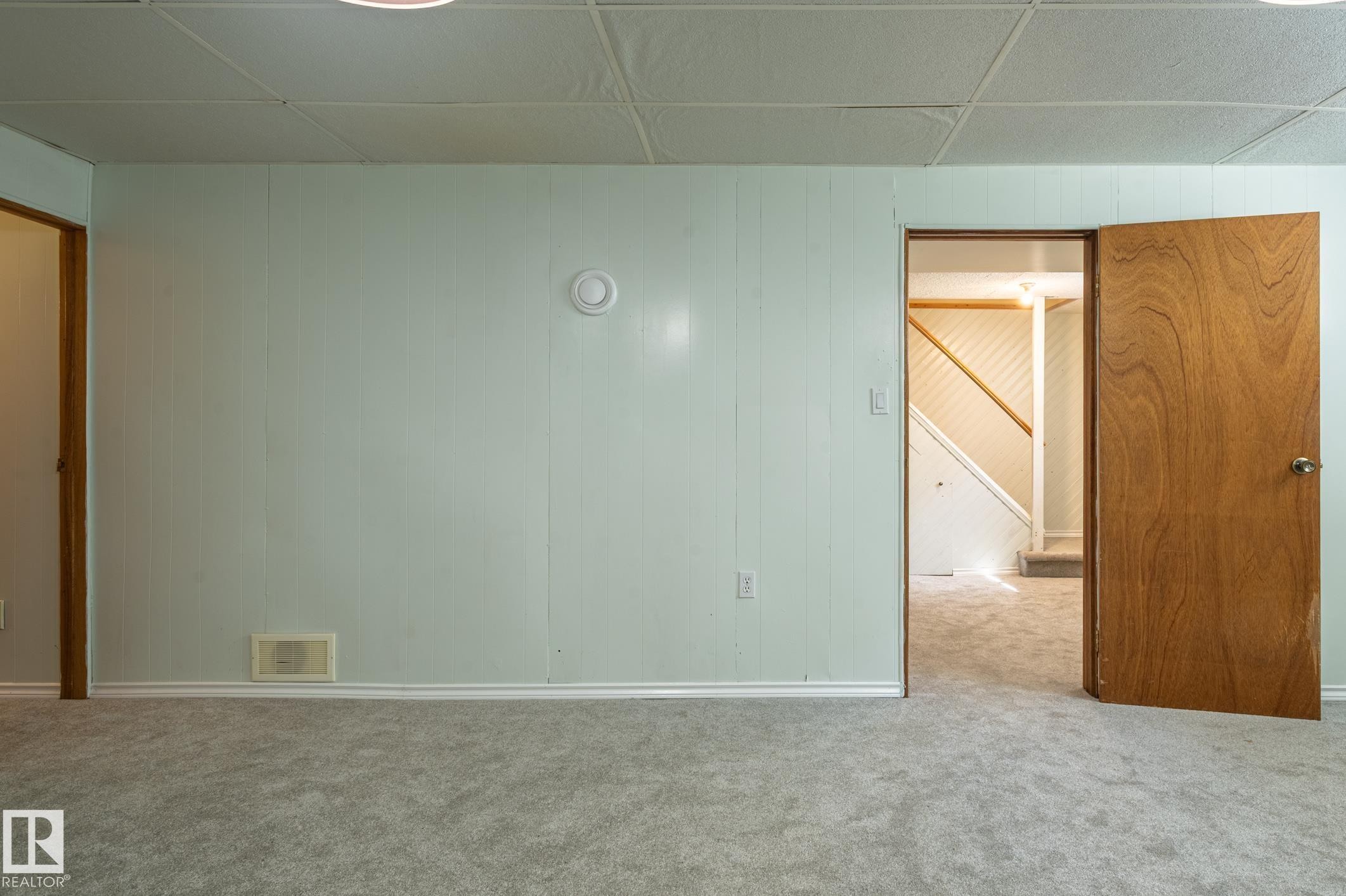 Carpeted room featuring light green paneled walls and a drop ceiling - 14708 108 Av, Edmonton, AB