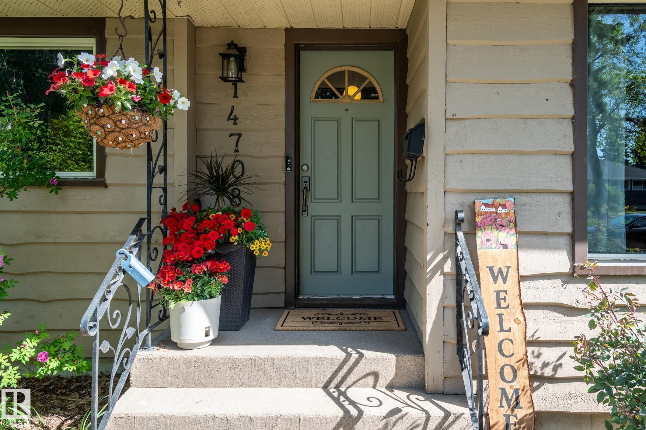 Front entry featuring a light blue paneled door with an arched glass insert, horizontal siding, concrete steps, and wrought iron handrails - 14708 108 Av, Edmonton, AB
