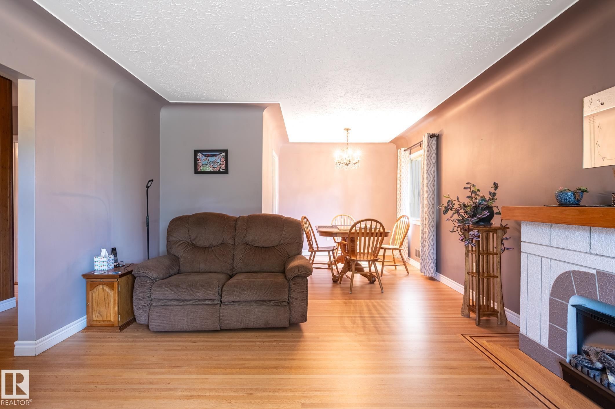 Hardwood-style flooring extends through the living area and into a formal dining space featuring a chandelier - 14708 108 Av, Edmonton, AB