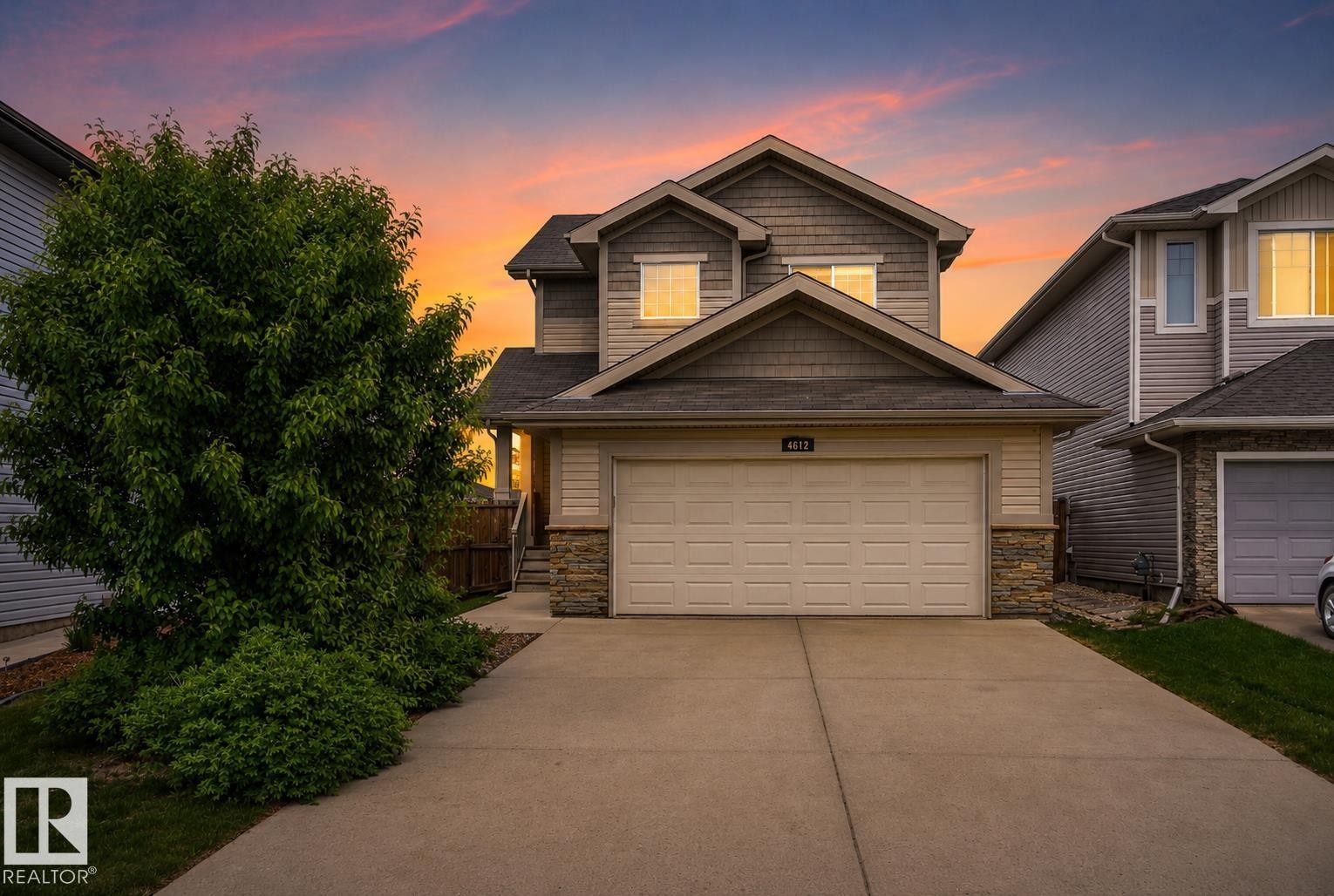 Two-story residence featuring light-colored siding, a prominent two-car garage, and a concrete driveway - 4612 Westcliff Point(E), Edmonton, AB