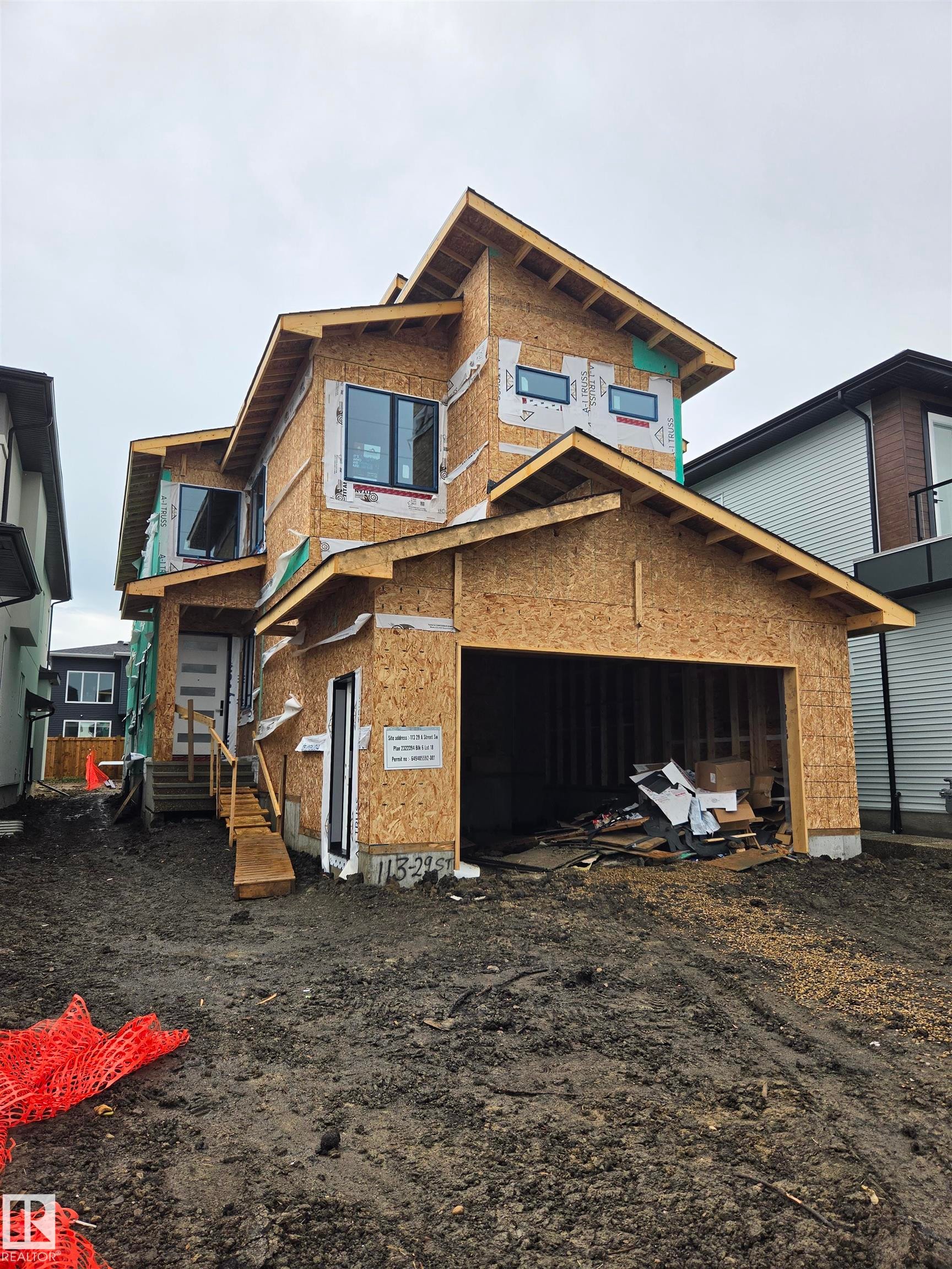 Multi-level new construction featuring a prominent front entrance, multiple contemporary windows, an attached garage, and a developing exterior - 113 29A Street, Edmonton, AB