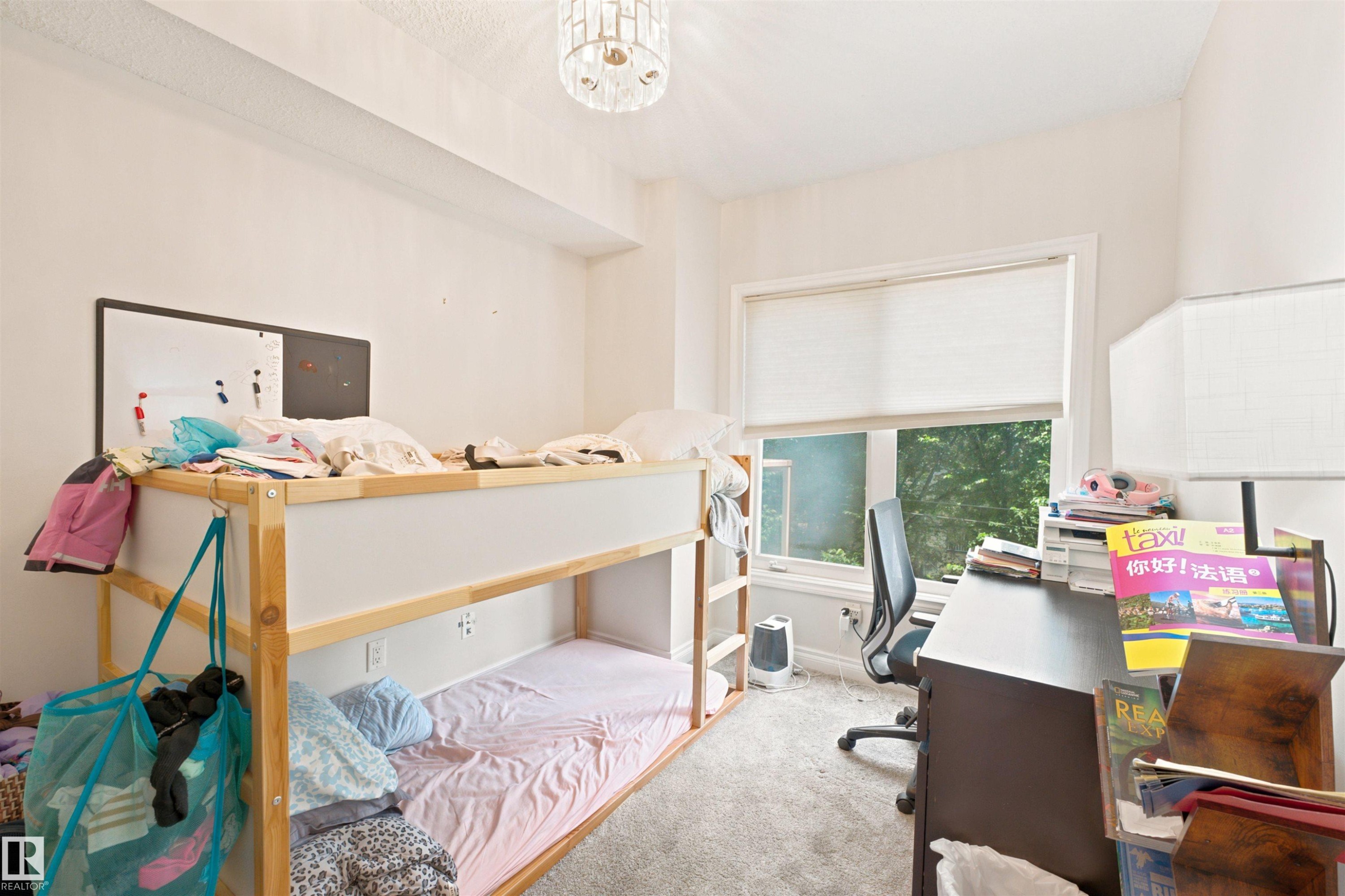 Bright interior space featuring a window with cellular shades, a contemporary ceiling light fixture, and textured carpeting - 305 11111 82 Avenue, Edmonton, AB