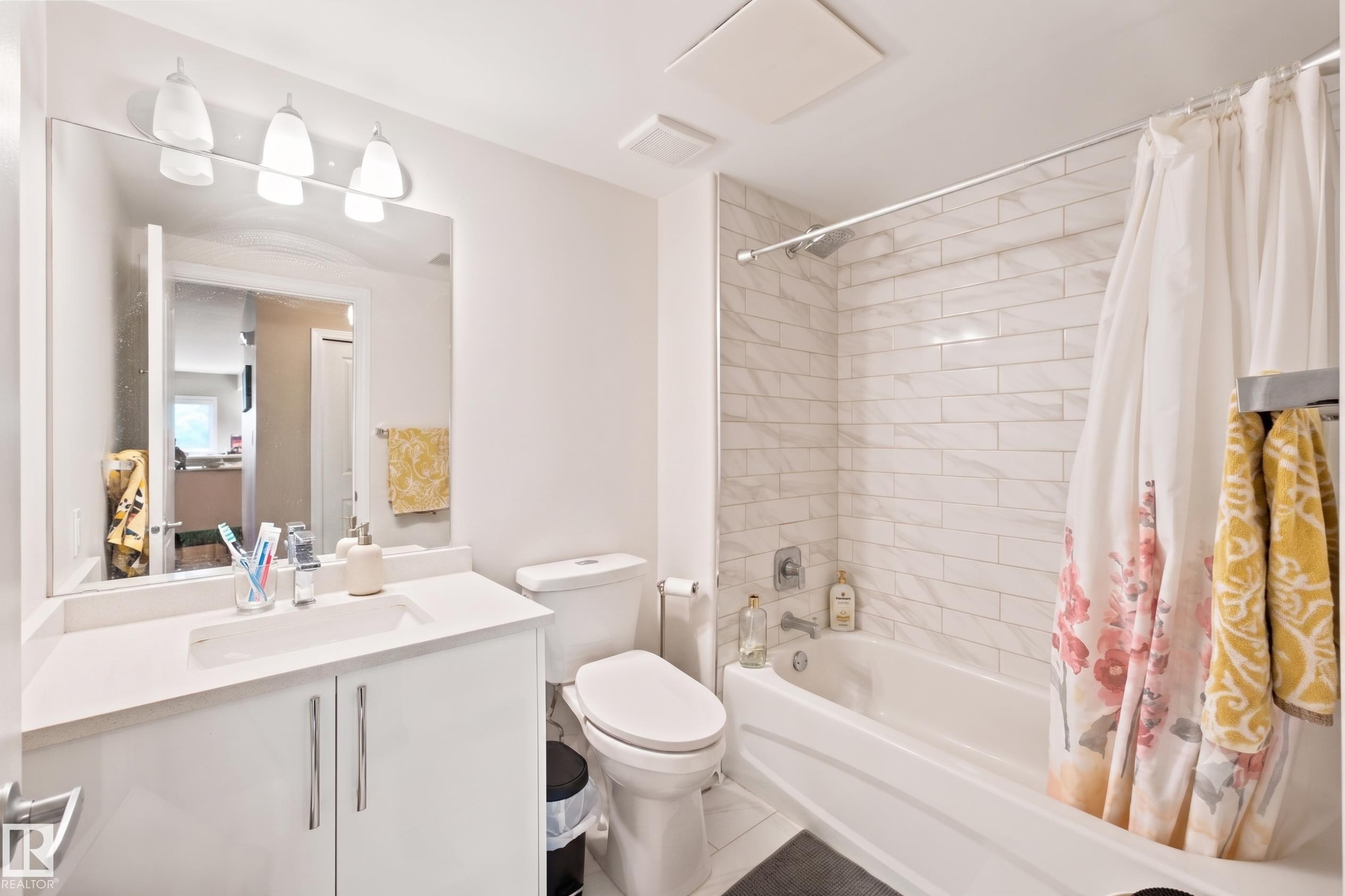 Bathroom featuring a white vanity with a rectangular undermount sink, a white countertop, and a large wall-mounted mirror - 305 11111 82 Avenue, Edmonton, AB