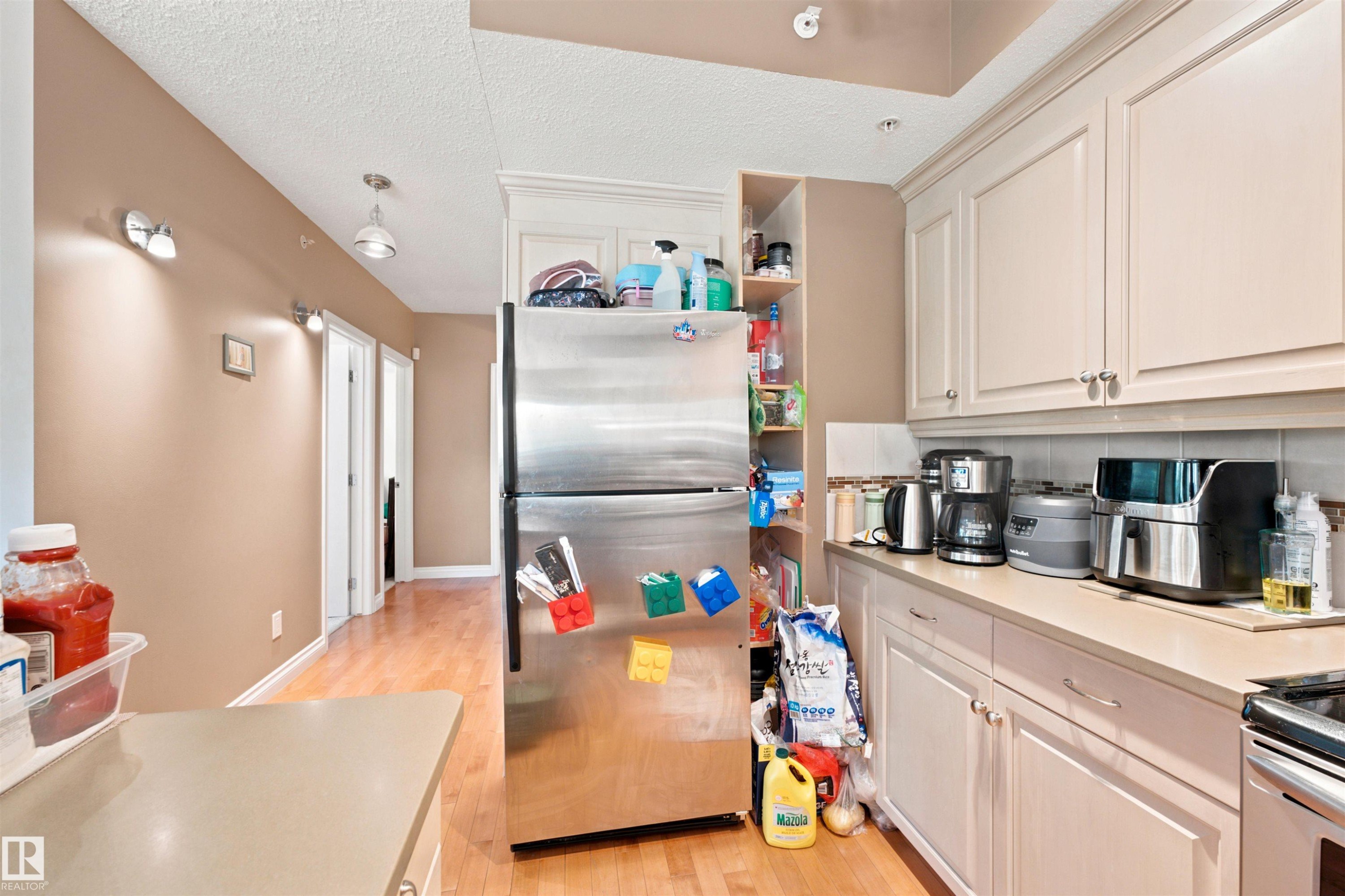 Kitchen featuring light-toned cabinetry, light countertops, and a white tile backsplash - 305 11111 82 Avenue, Edmonton, AB