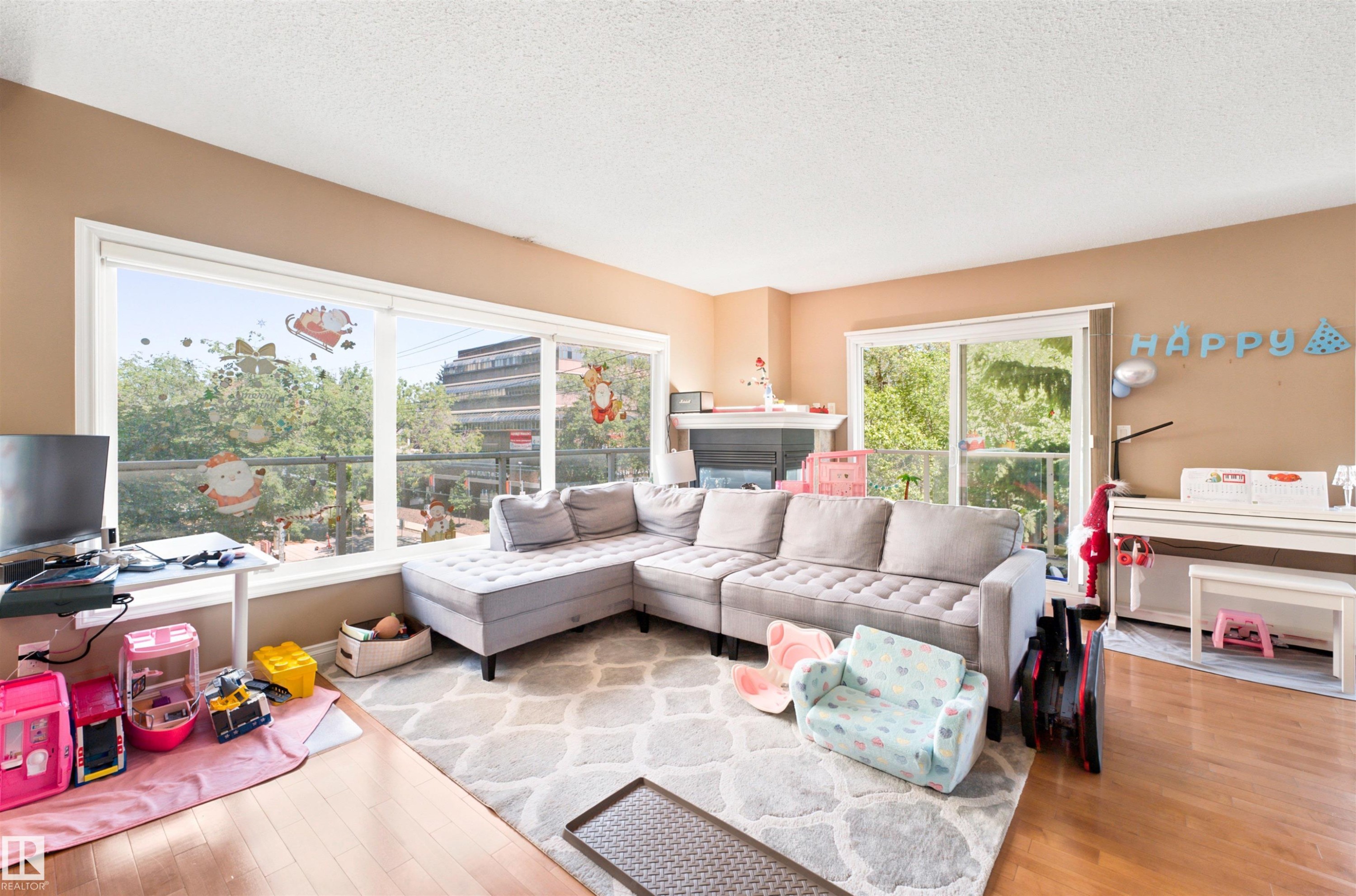 Living area featuring expansive windows, a glass sliding door, and a fireplace with a white mantel - 305 11111 82 Avenue, Edmonton, AB