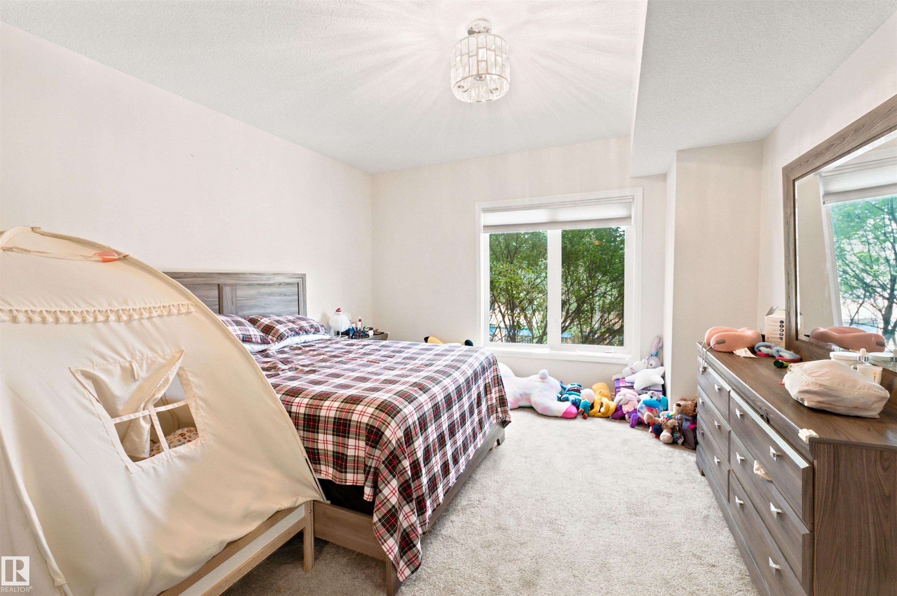 Bedroom featuring a large window, neutral wall paint, and plush carpet flooring - 305 11111 82 Avenue, Edmonton, AB
