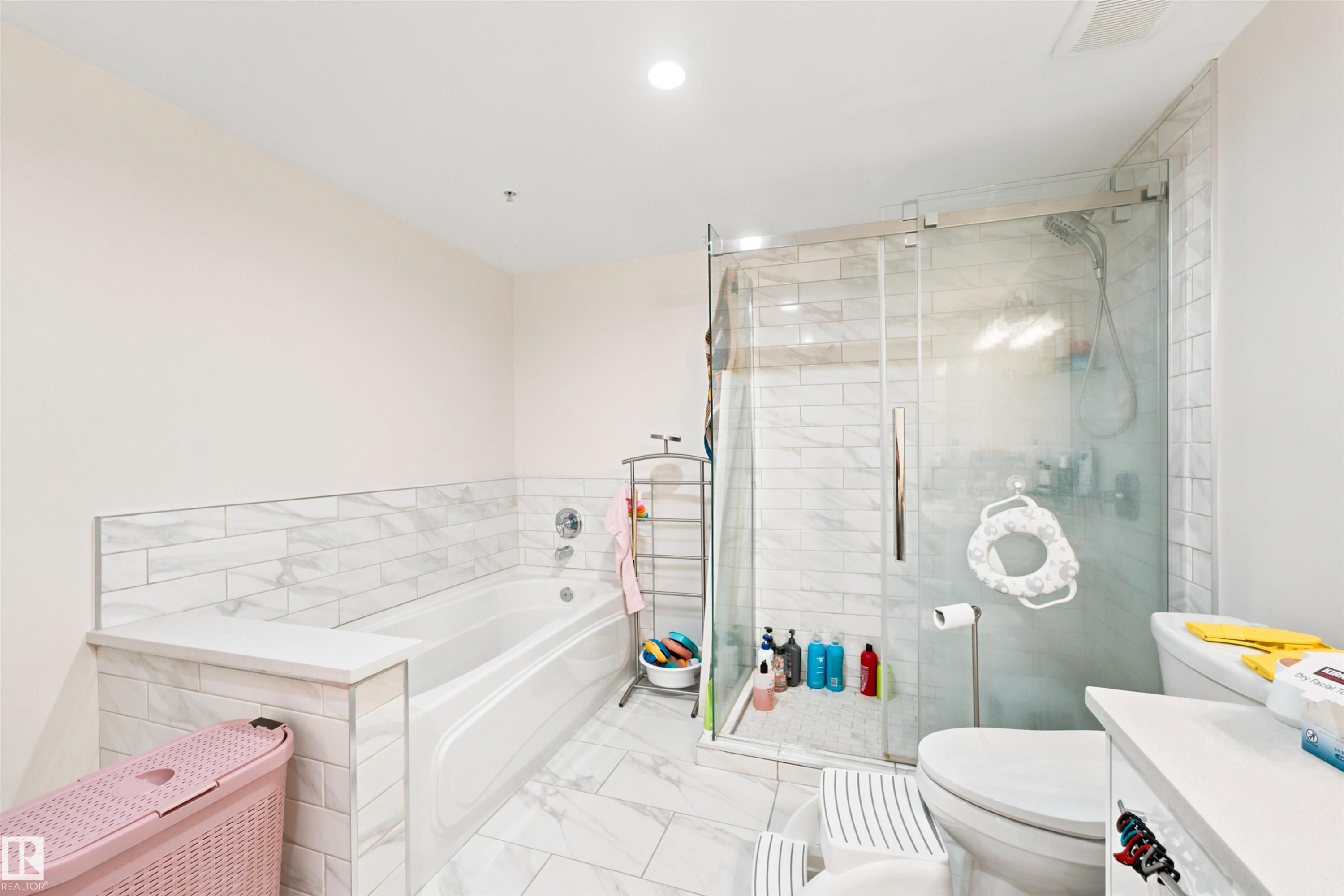 Bathroom featuring a built-in tub, a glass-enclosed shower with subway tile surround, and a coordinating tiled floor - 305 11111 82 Avenue, Edmonton, AB