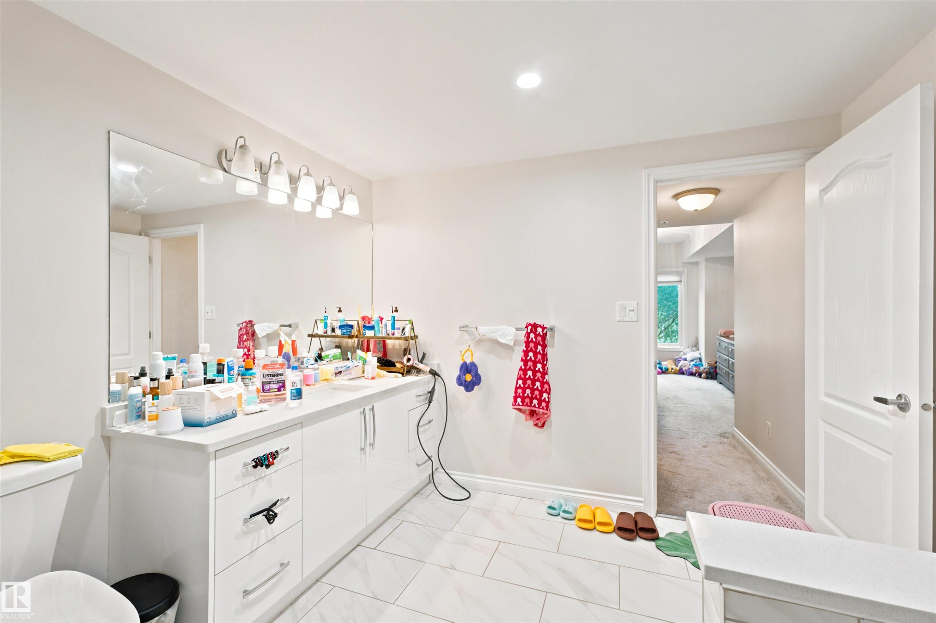 Bathroom featuring a double vanity with white cabinetry, a large wall-mounted mirror, and a six-light fixture - 305 11111 82 Avenue, Edmonton, AB