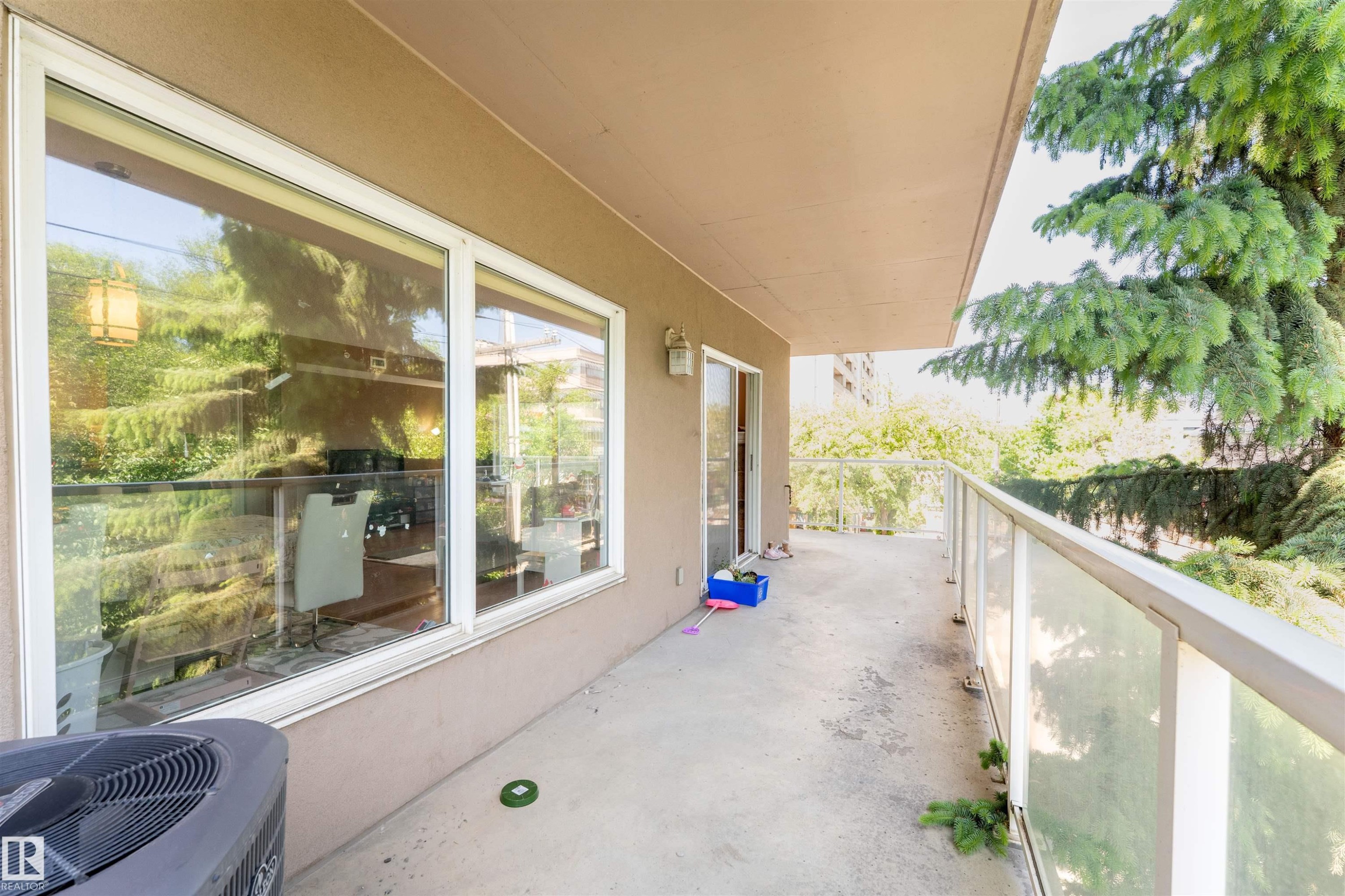 Spacious concrete balcony with a glass railing system and a sliding glass door for outdoor access - 305 11111 82 Avenue, Edmonton, AB