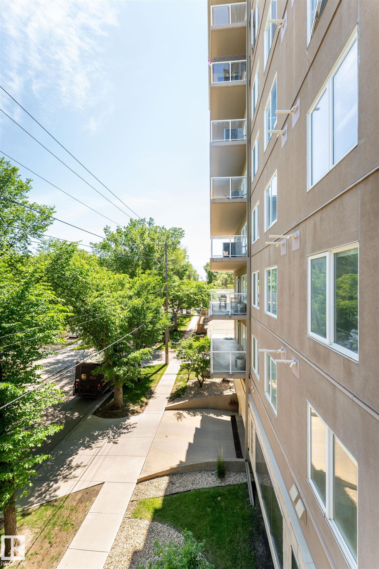 Multi-story building featuring a neutral-toned facade and multiple private balconies with glass railings - 305 11111 82 Avenue, Edmonton, AB