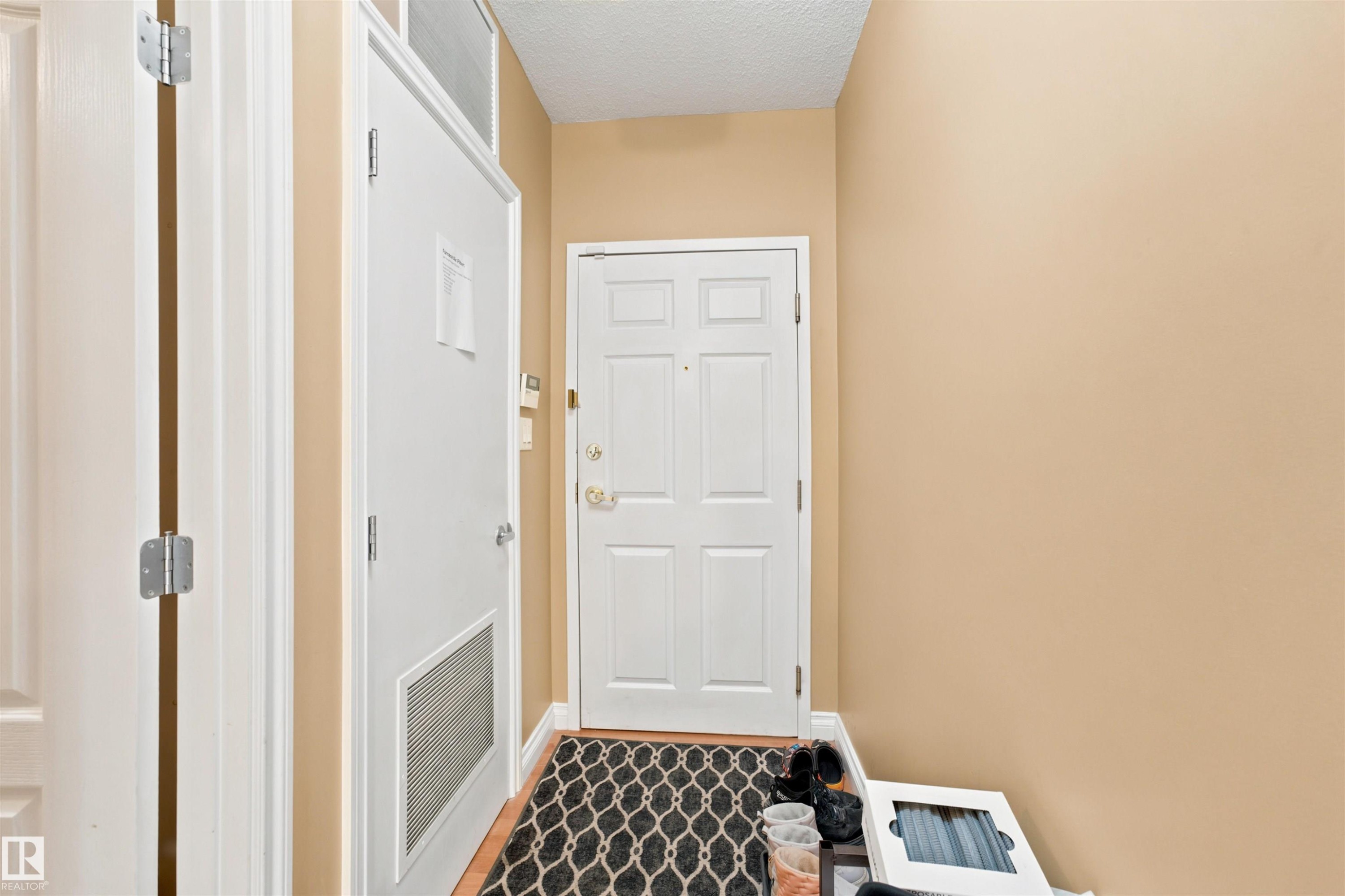 Entryway featuring a paneled door, wood-finish flooring, and neutral wall paint - 305 11111 82 Avenue, Edmonton, AB