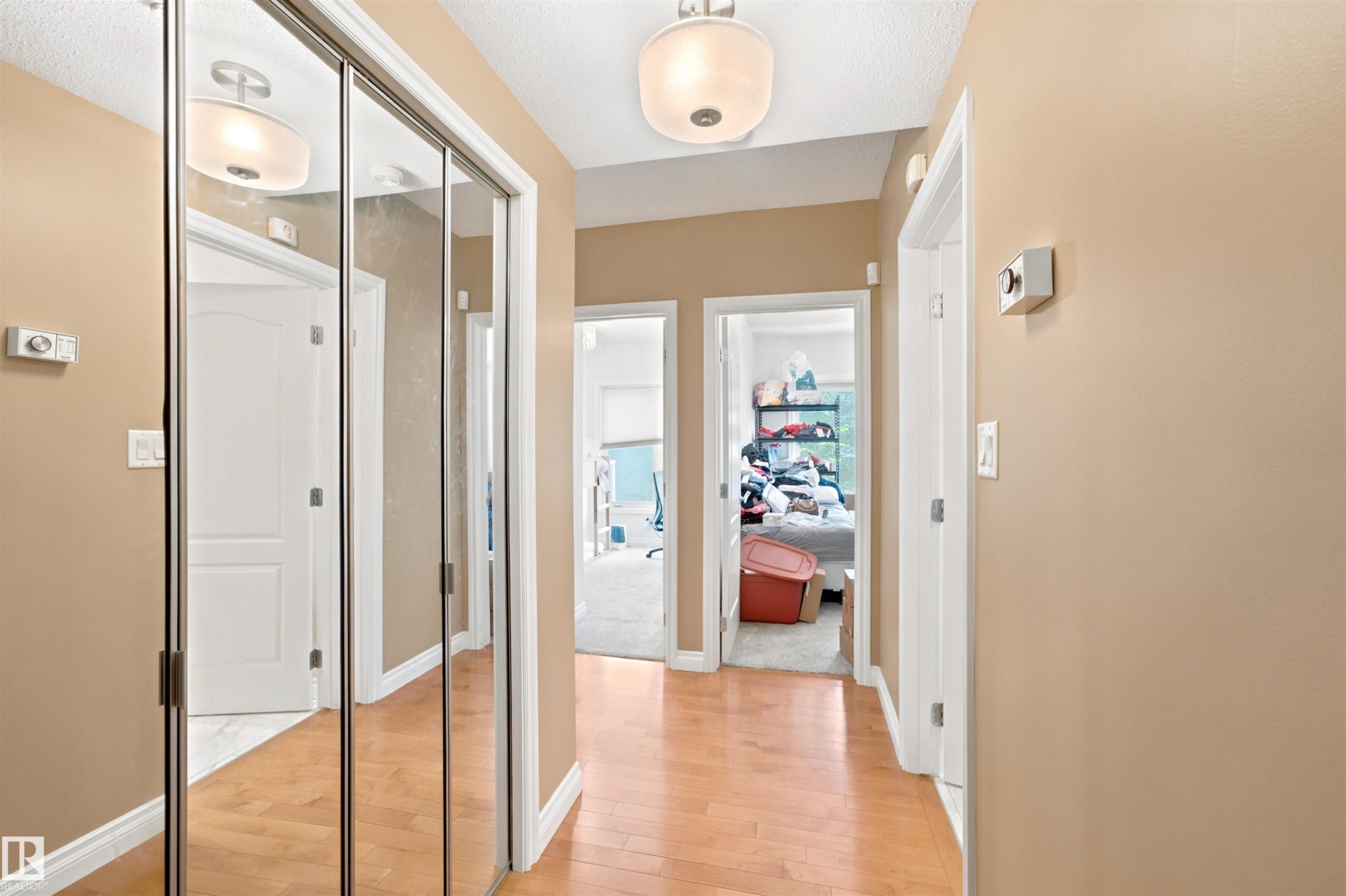 Hallway featuring wood-finish flooring, neutral wall paint, and multiple doorways - 305 11111 82 Avenue, Edmonton, AB