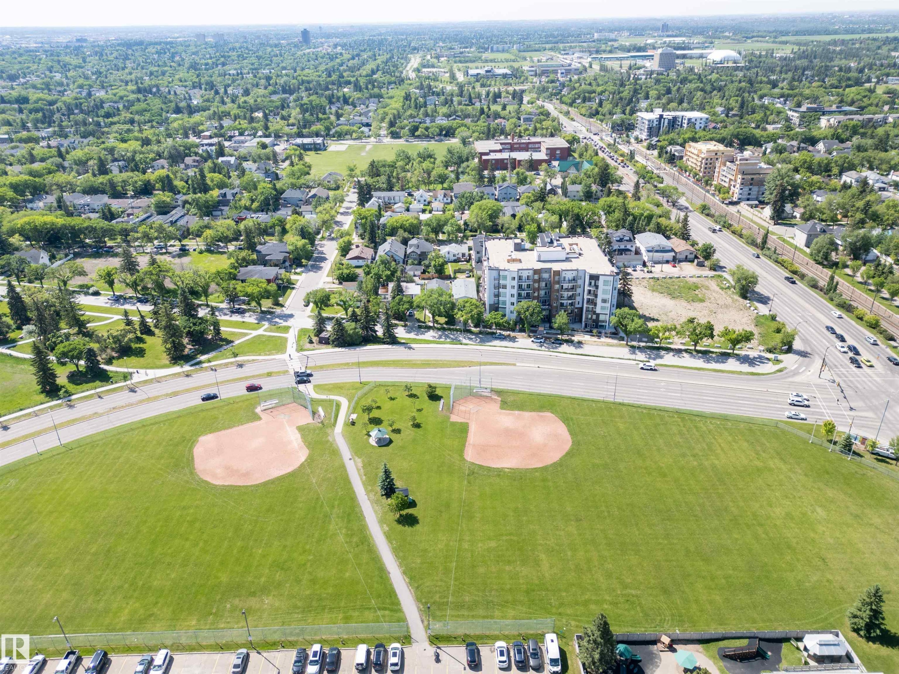 Expansive green space featuring two baseball fields, surrounded by mature trees, paved pathways, and a network of roadways - 305 11111 82 Avenue, Edmonton, AB
