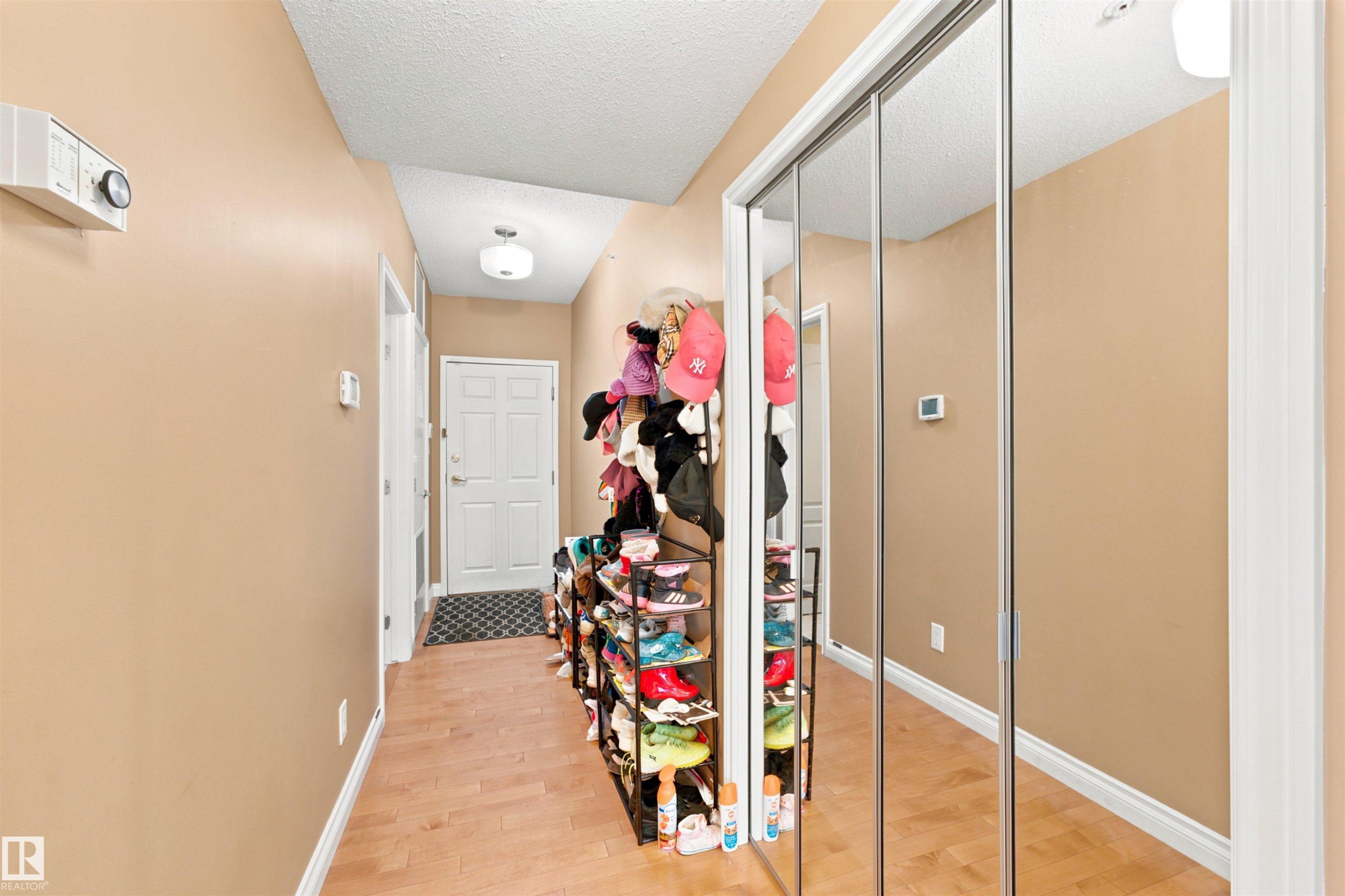 Entryway featuring wood-finish flooring, light beige wall paint, and white baseboards - 305 11111 82 Avenue, Edmonton, AB
