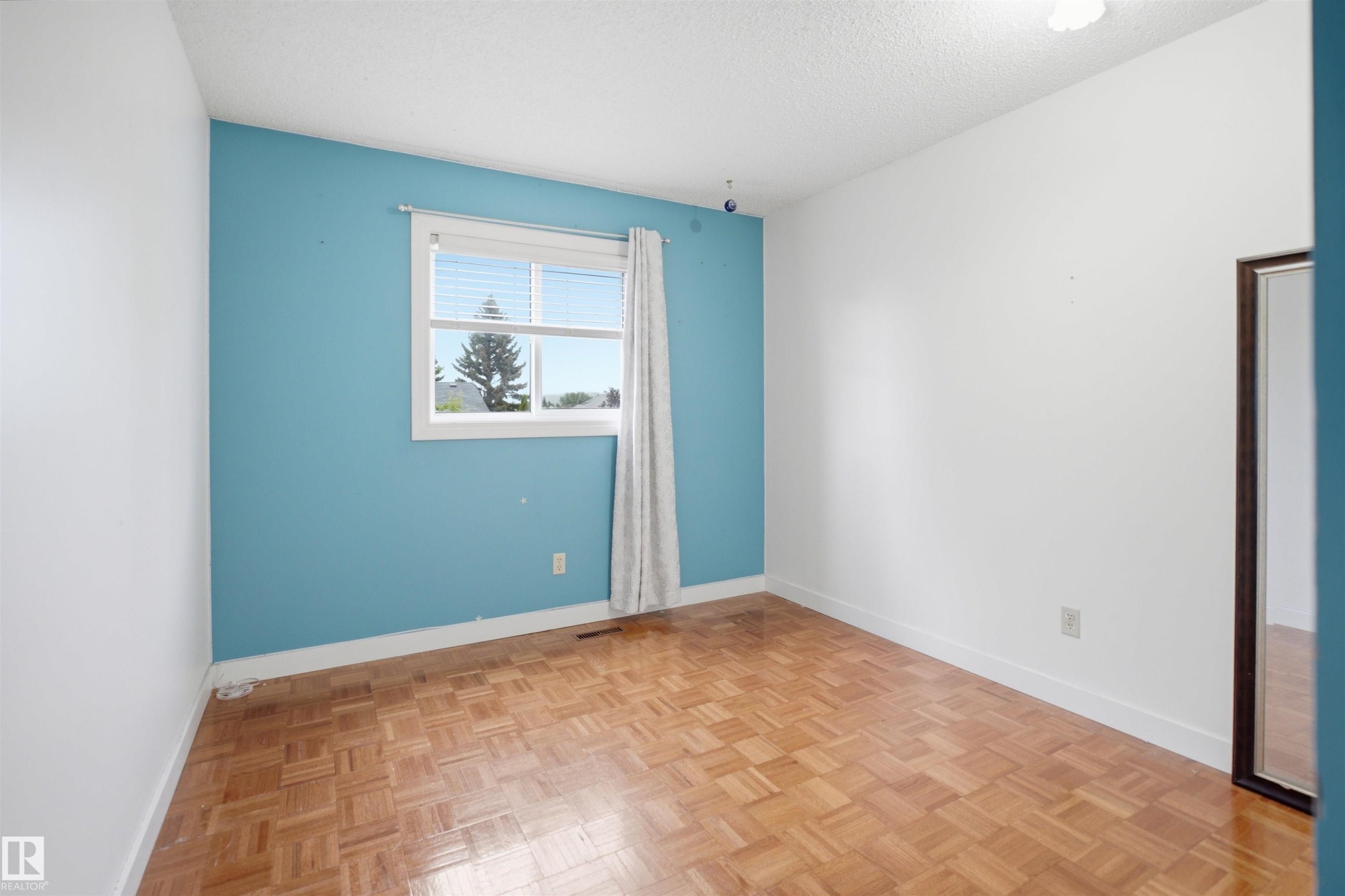 Room featuring wood-finish parquet flooring and white baseboards - 3220 42A Avenue, Edmonton, AB