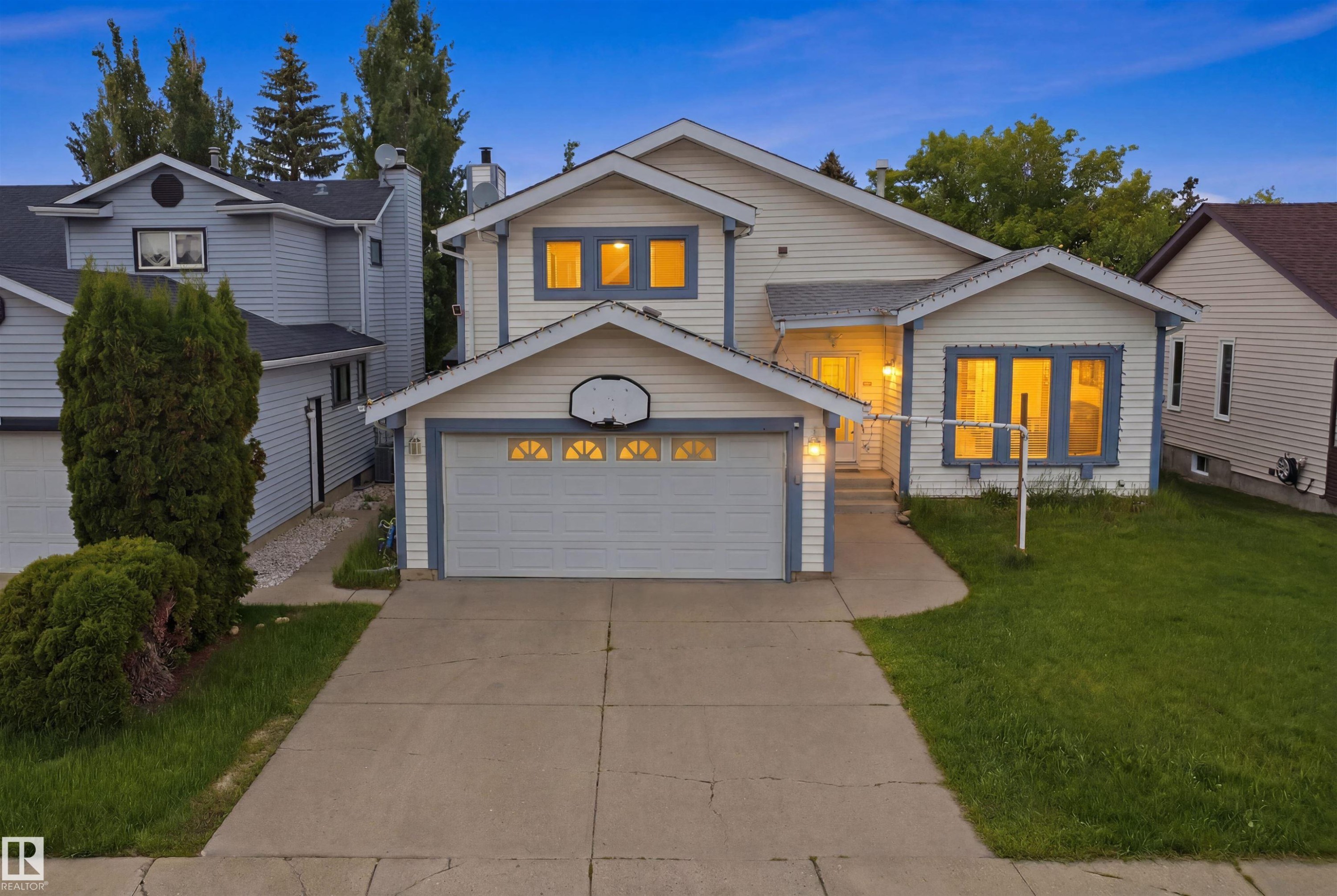 Two-story detached residence featuring light-colored siding, a two-car garage with a white door, and contrasting blue trim accents - 3220 42A Avenue, Edmonton, AB
