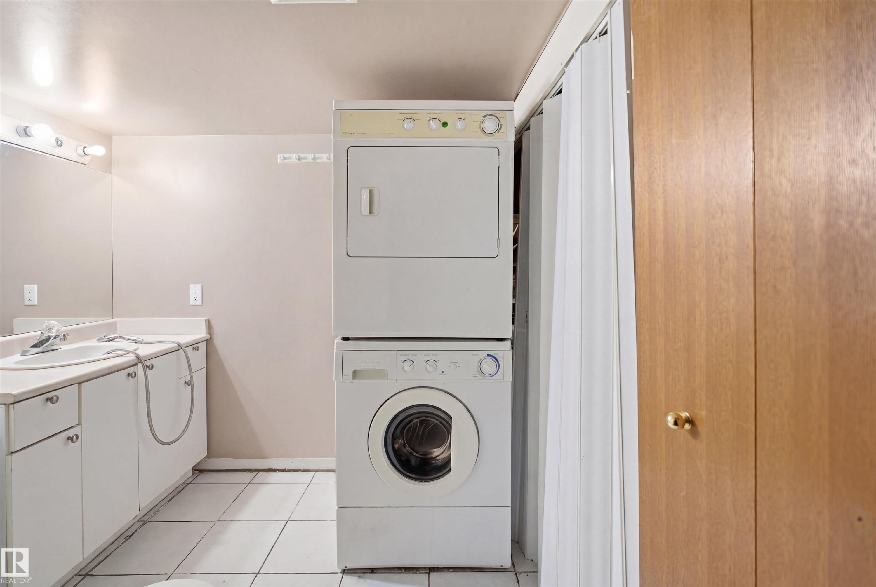 Utility area featuring a stacked washer and dryer, tile flooring, and a vanity with an integrated sink - 3220 42A Avenue, Edmonton, AB