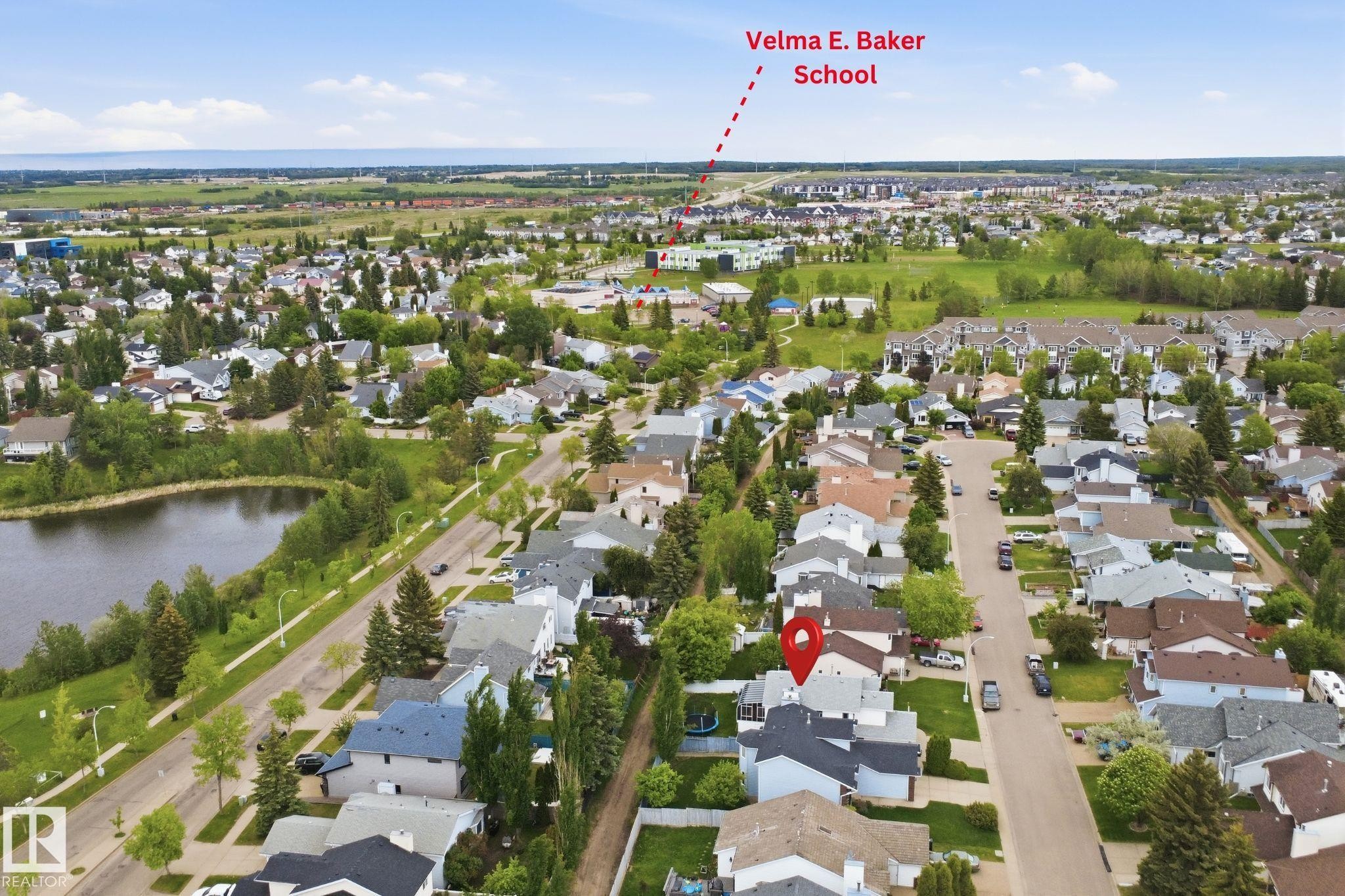 Aerial perspective showcasing a residential neighborhood with a large pond and green spaces - 3220 42A Avenue, Edmonton, AB