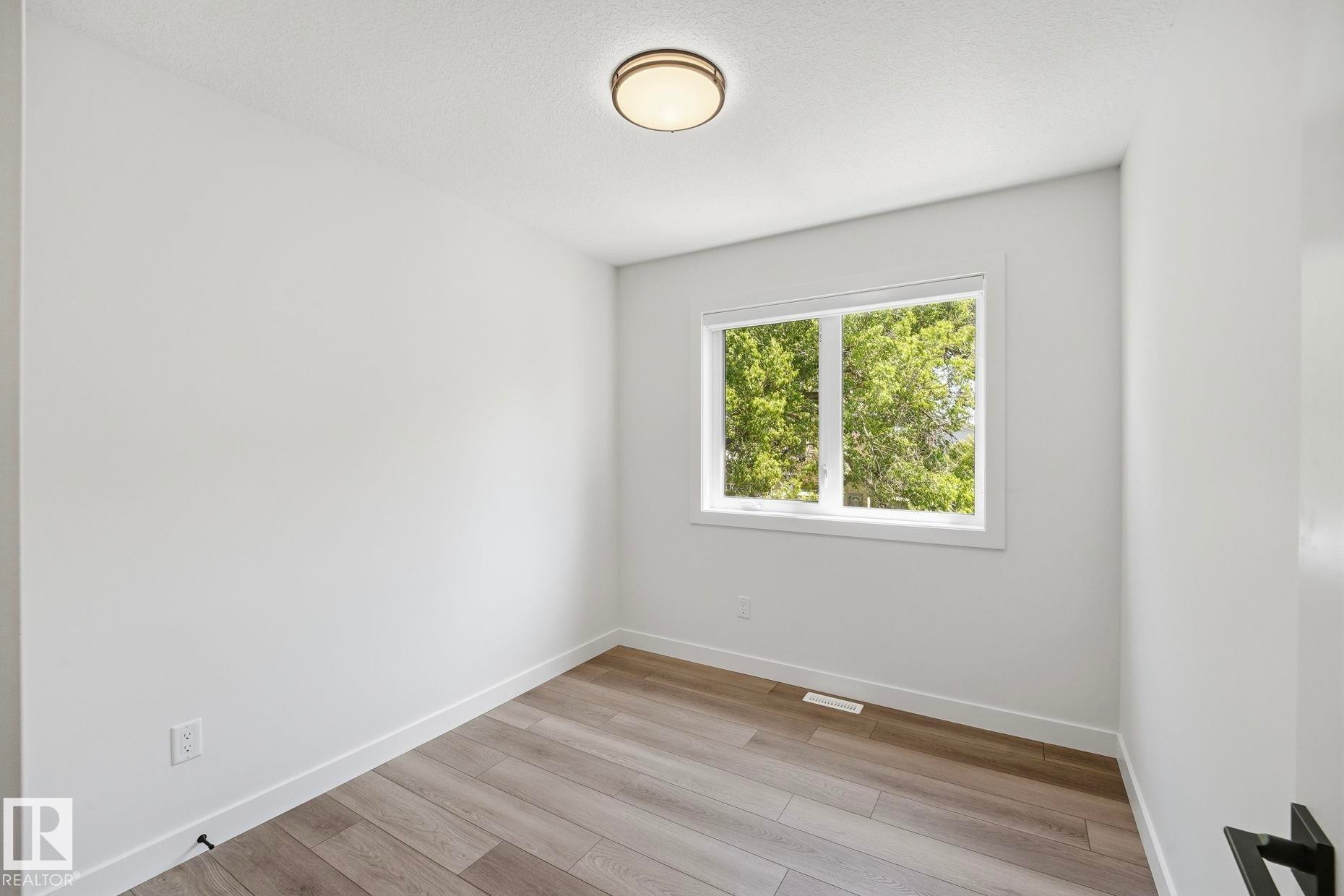 Interior room featuring wood-finish flooring and a contemporary flush-mount ceiling light - 11012 132 Street, Edmonton, AB