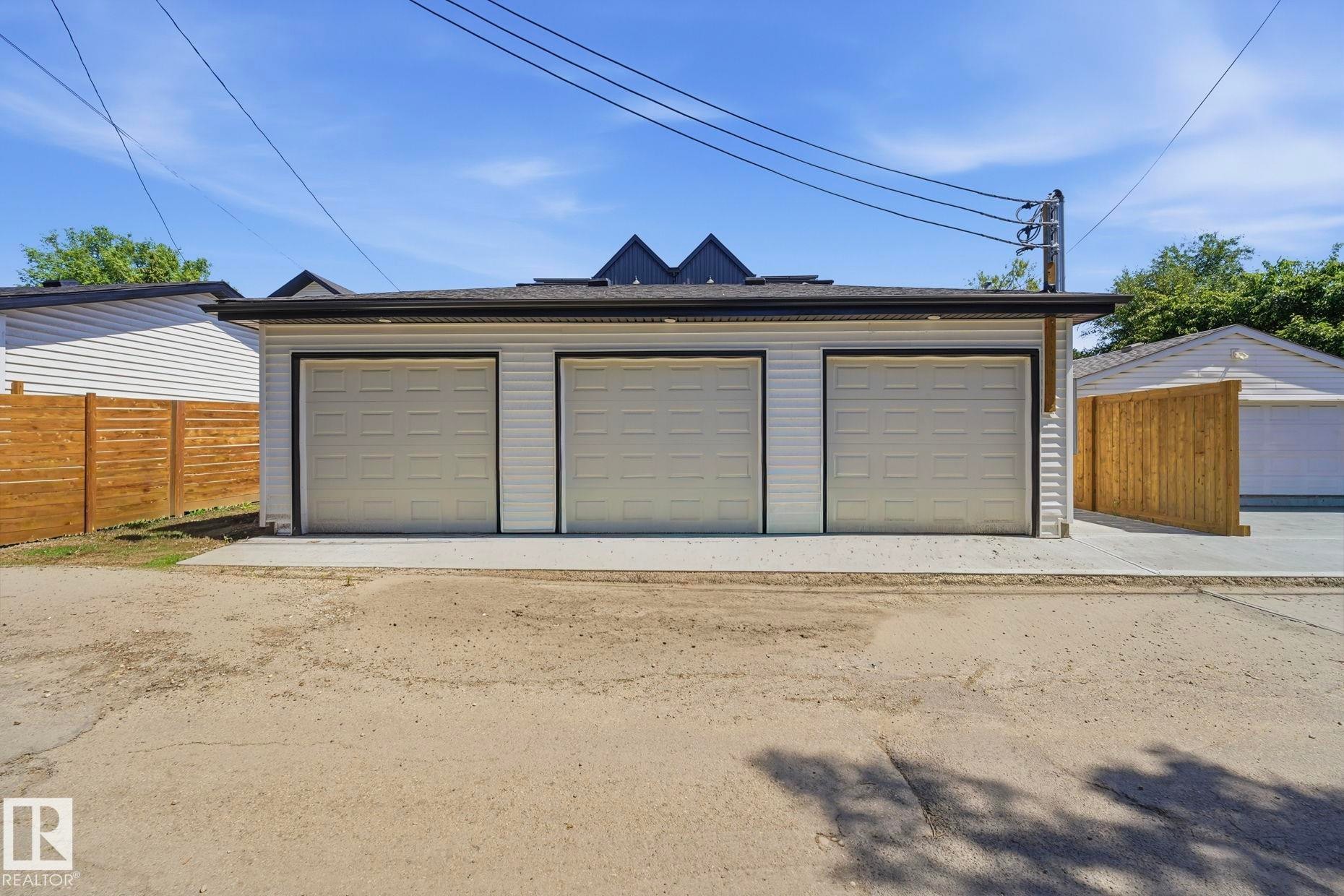 Detached three-car garage featuring white siding and individual overhead doors - 11012 132 Street, Edmonton, AB