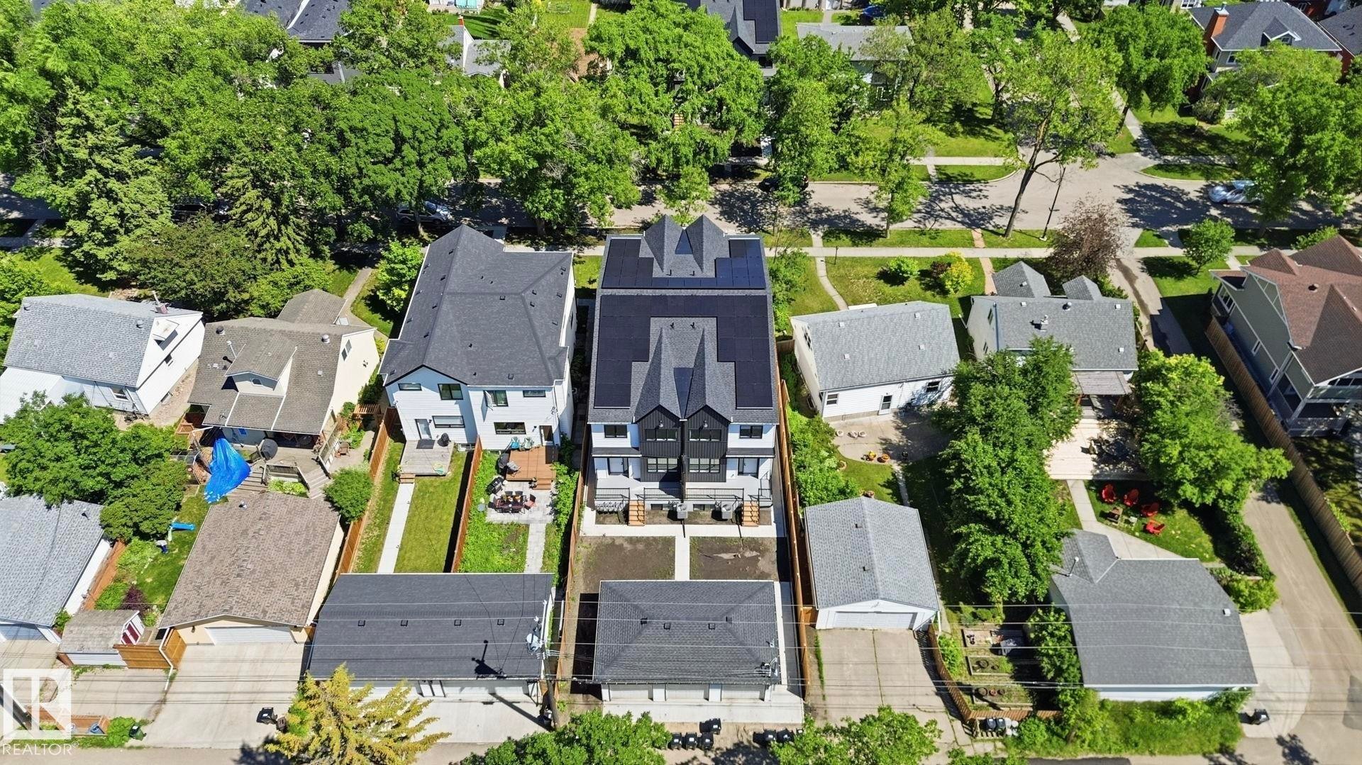 Modern duplex structure featuring a dark gray exterior, multiple pitched roofs, and solar panels - 11012 132 Street, Edmonton, AB