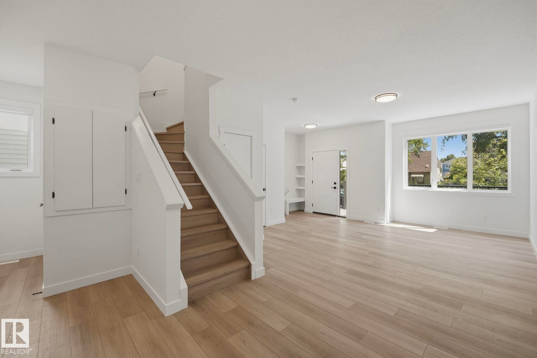 Open-concept living area with wood-finish flooring, white walls, and recessed lighting - 11012 132 Street, Edmonton, AB