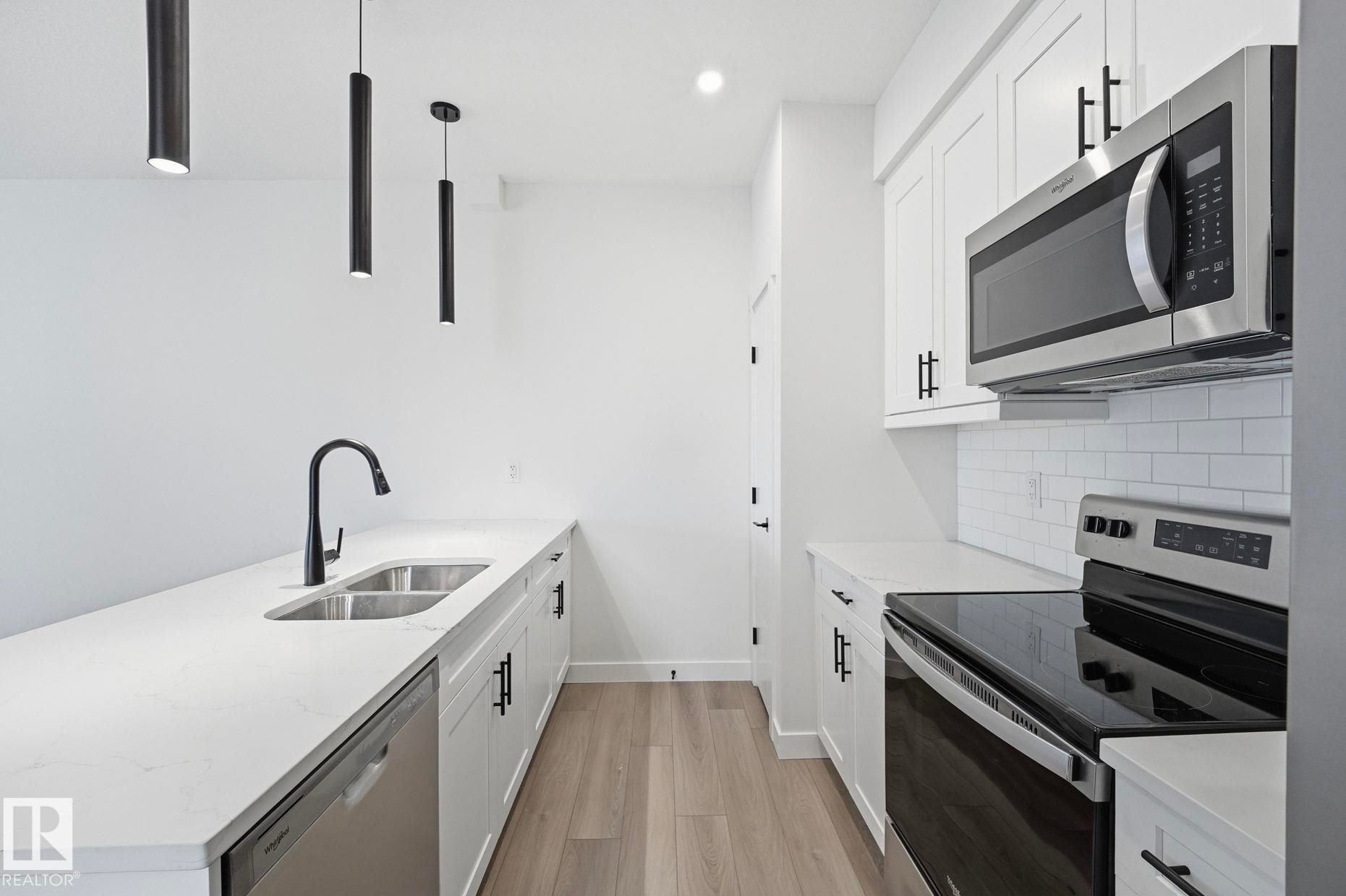 Modern kitchen featuring white cabinetry, quartz countertops, and stainless steel appliances - 11012 132 Street, Edmonton, AB