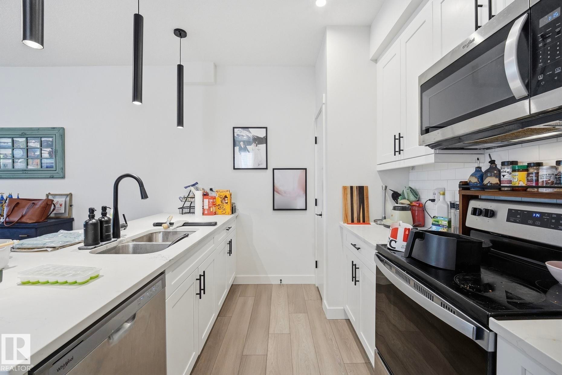 Modern kitchen with white cabinetry and light wood-finish flooring - 11007 132 Street, Edmonton, AB