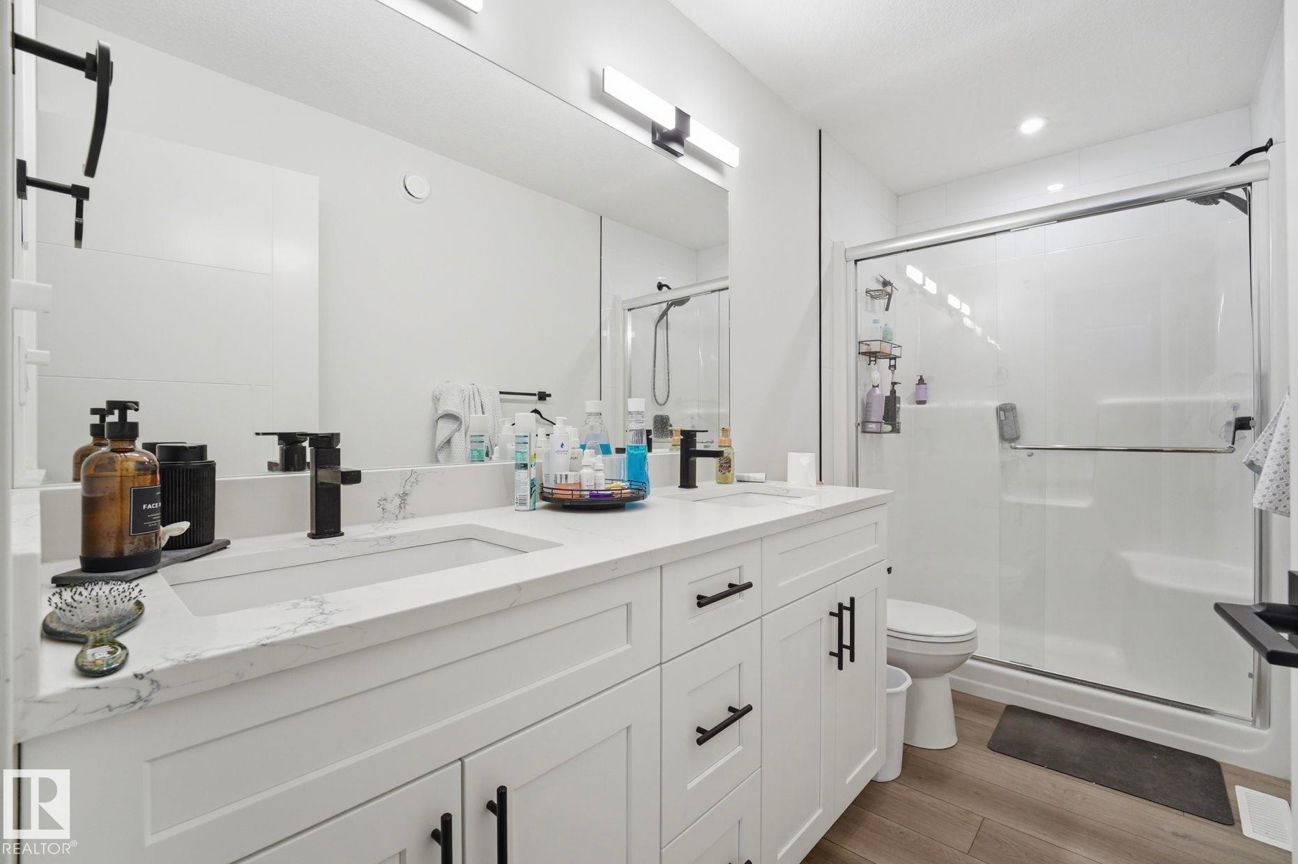 Dual sink vanity with white cabinetry, integrated sinks, and dark-finish fixtures - 11007 132 Street, Edmonton, AB