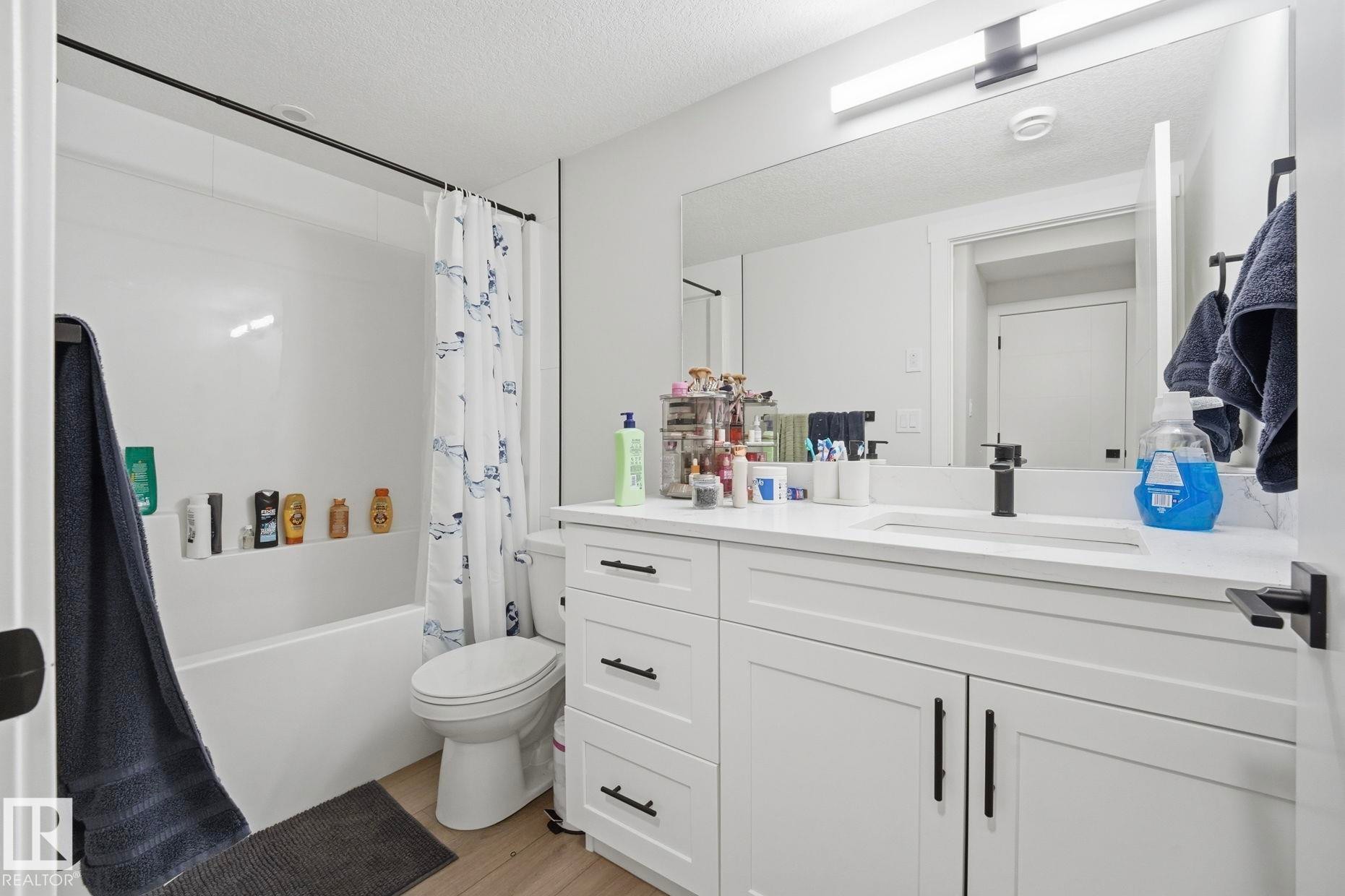 Modern bathroom featuring a white vanity with shaker-style cabinetry, quartz countertop, and rectangular undermount sink - 11007 132 Street, Edmonton, AB