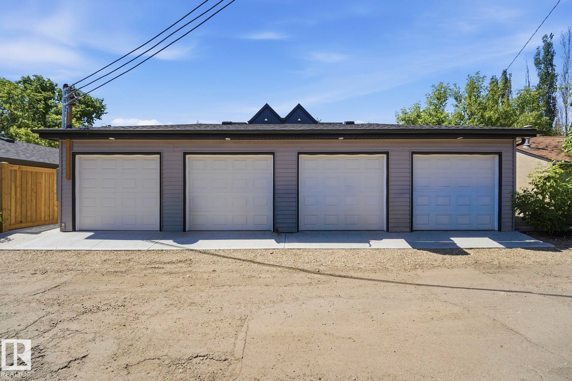 Four single-car garage bays with white panel doors and black trim - 11007 132 Street, Edmonton, AB