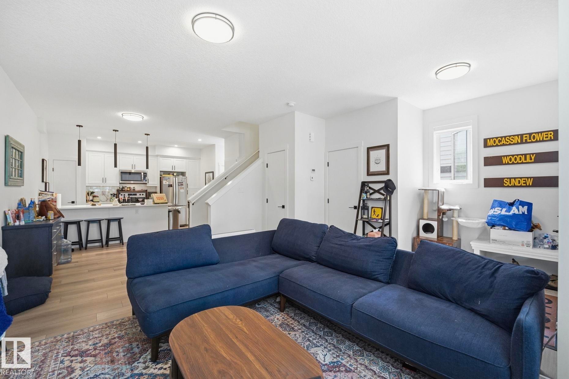 Bright living area featuring wood-finish flooring, white walls, and contemporary ceiling light fixtures - 11007 132 Street, Edmonton, AB
