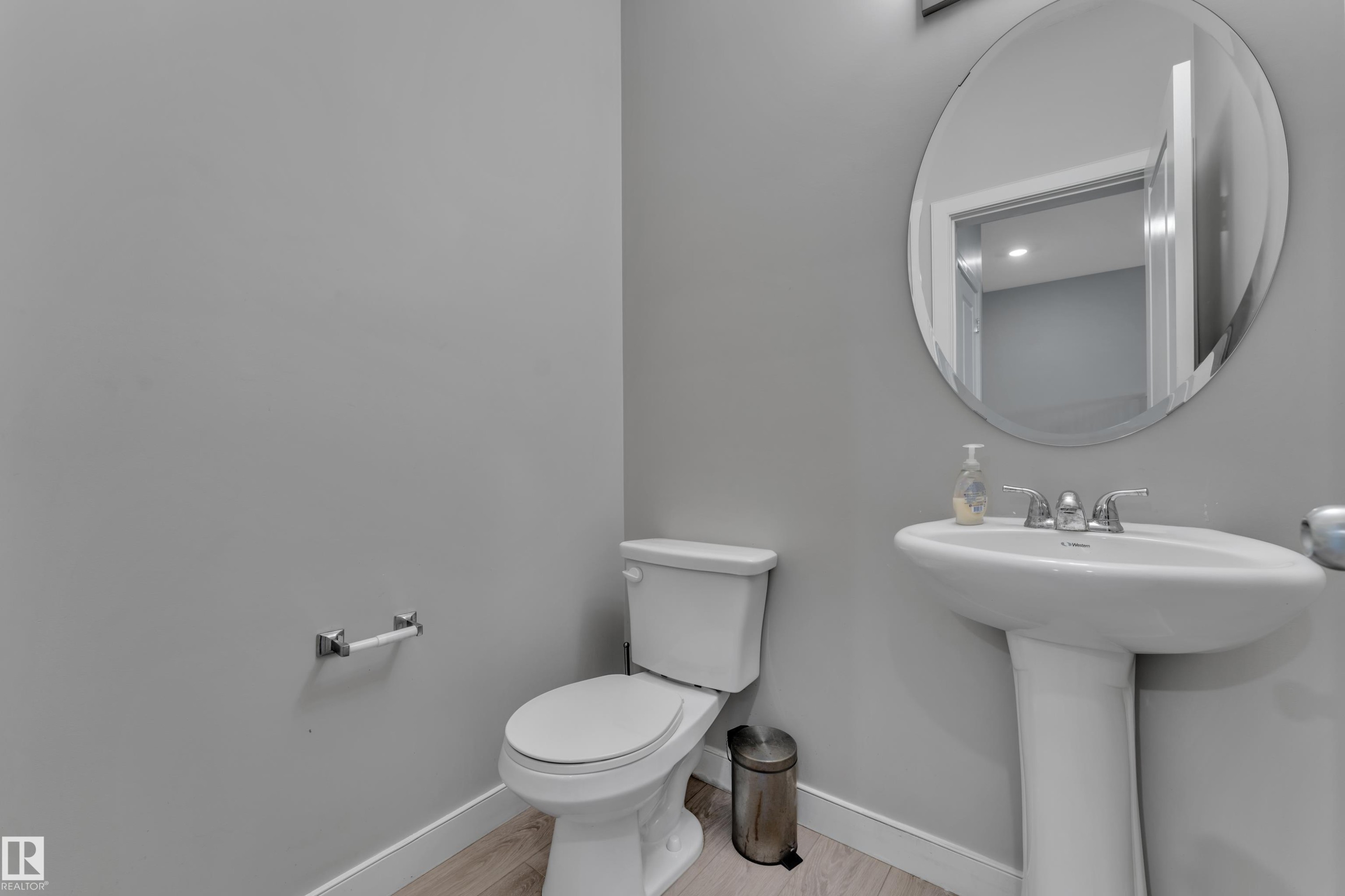 Pedestal sink with chrome fixtures and an oval frameless mirror - 9328 Pear Link Link, Edmonton, AB