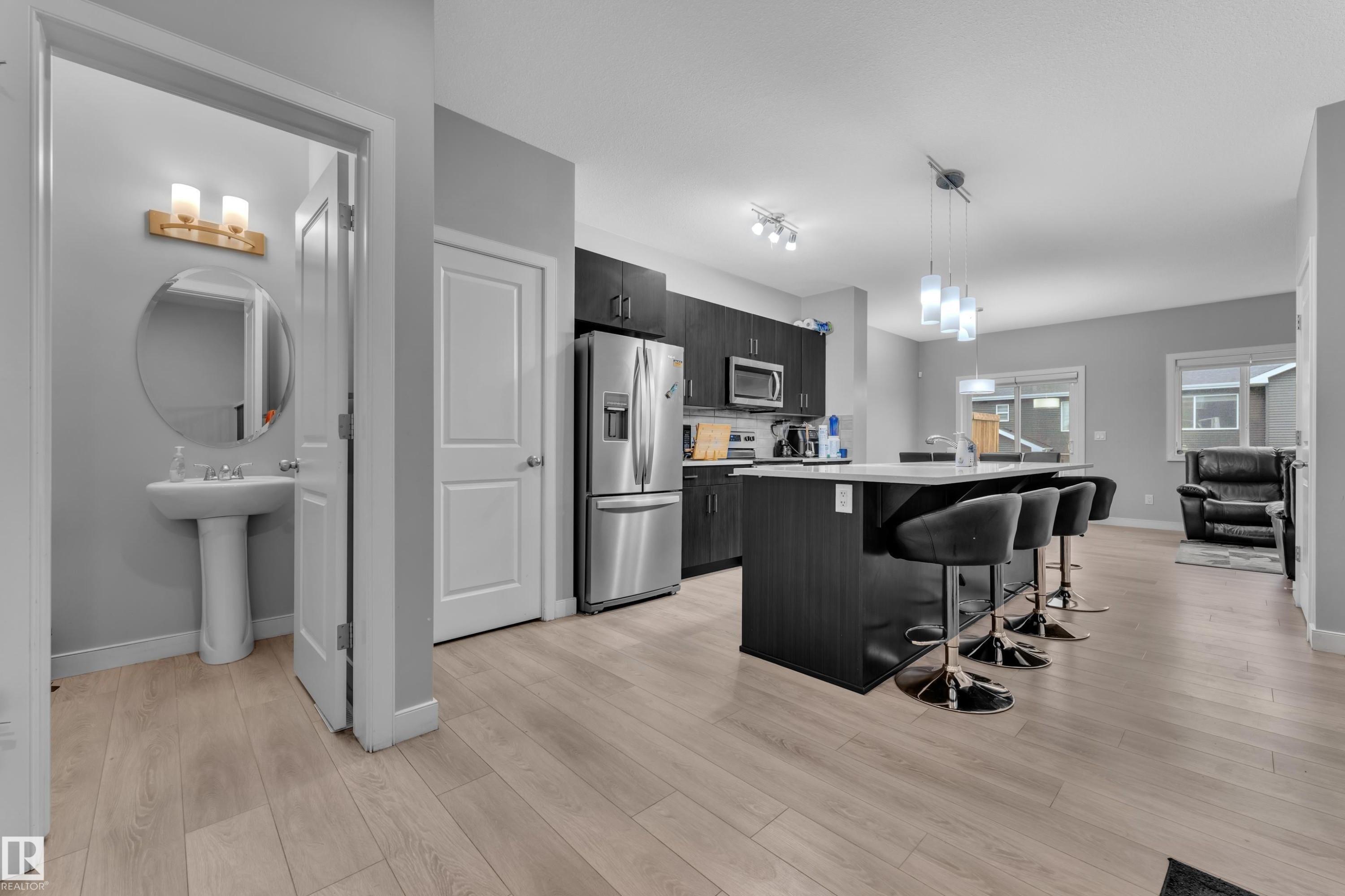 Modern kitchen featuring dark wood-finish cabinetry, stainless steel appliances, and a central island with a light-toned countertop - 9328 Pear Link Link, Edmonton, AB
