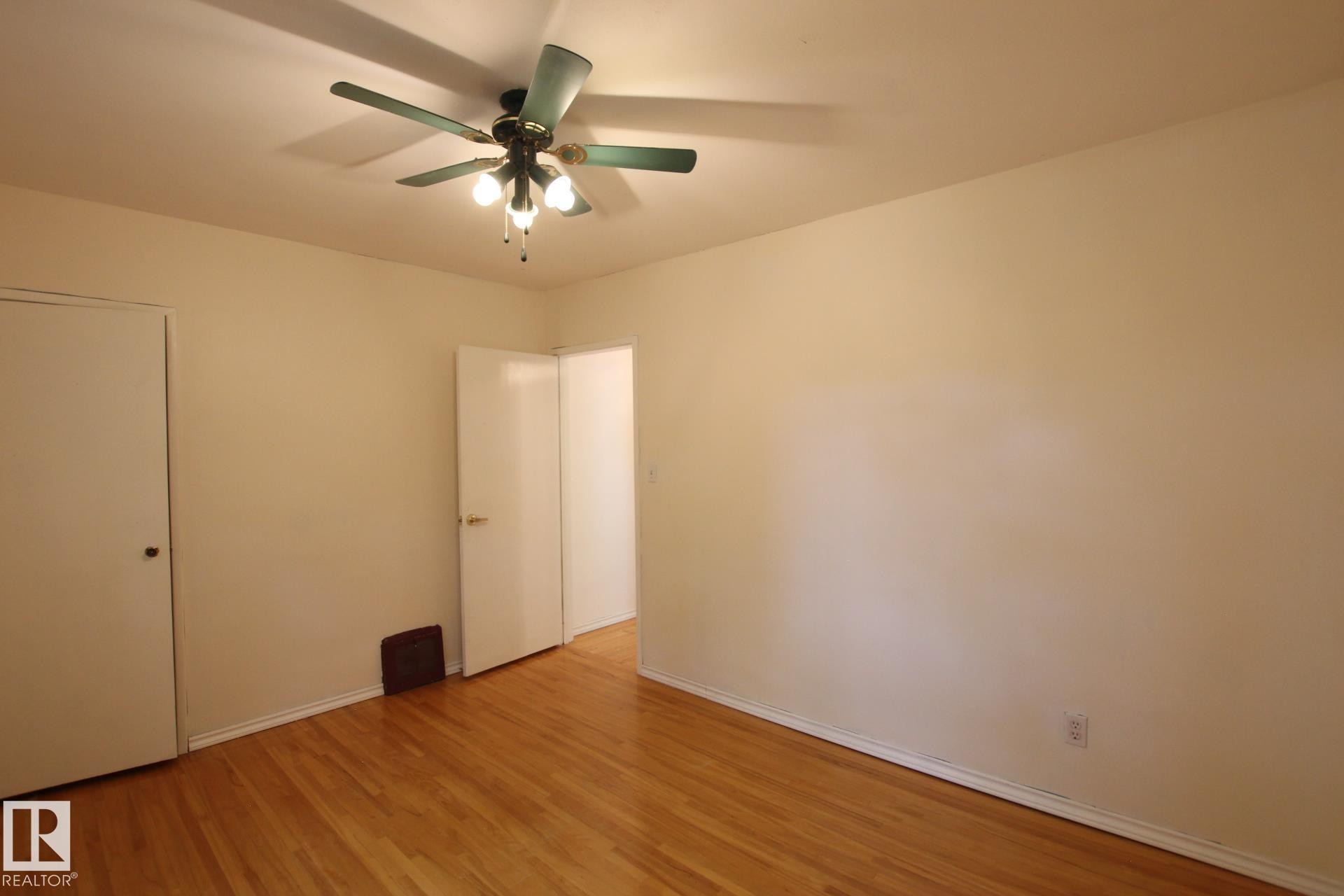 Room featuring wood-finish flooring, a ceiling fan with integrated lighting, and neutral wall paint - 11242 56 Street, Edmonton, AB