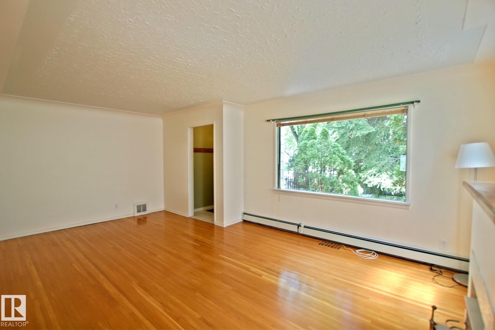 Spacious interior featuring hardwood flooring, white wall paint, and crown molding - 11242 56 Street, Edmonton, AB
