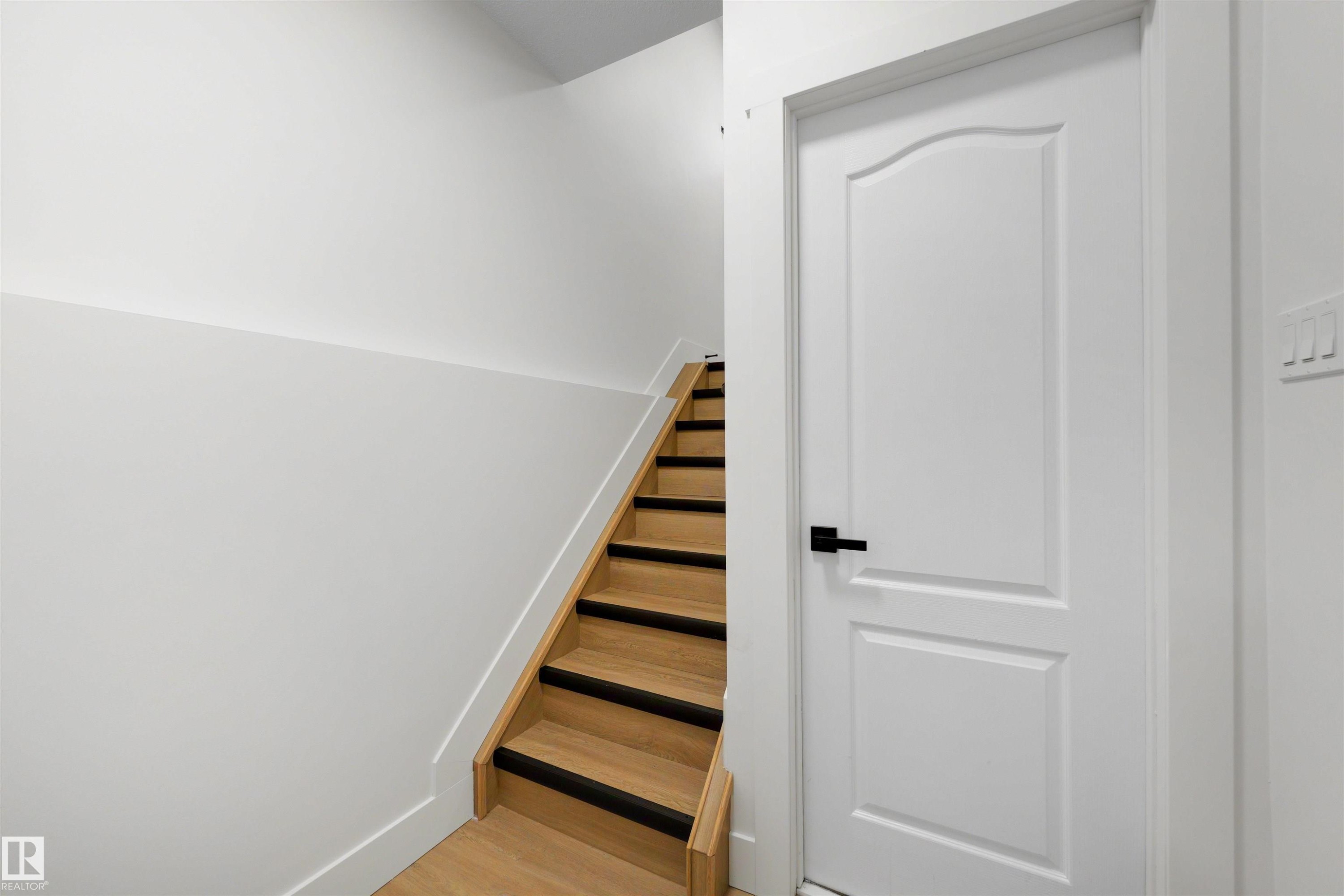 Natural wood-finish staircase with black tread accents and crisp white risers - 12611 47 Street, Edmonton, AB