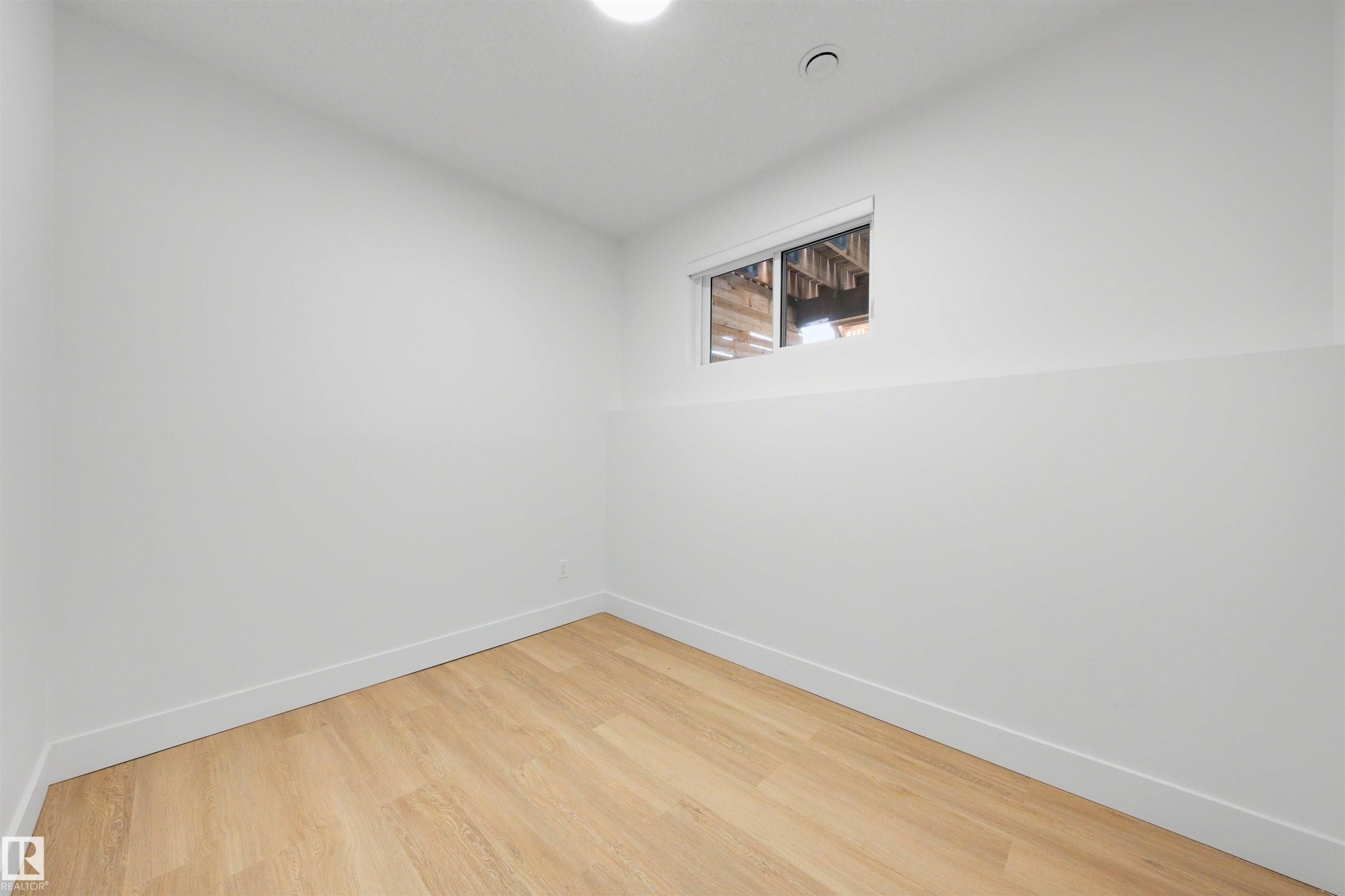 White painted walls with a small window, light wood-finish flooring, and recessed ceiling lighting - 12611 47 Street, Edmonton, AB