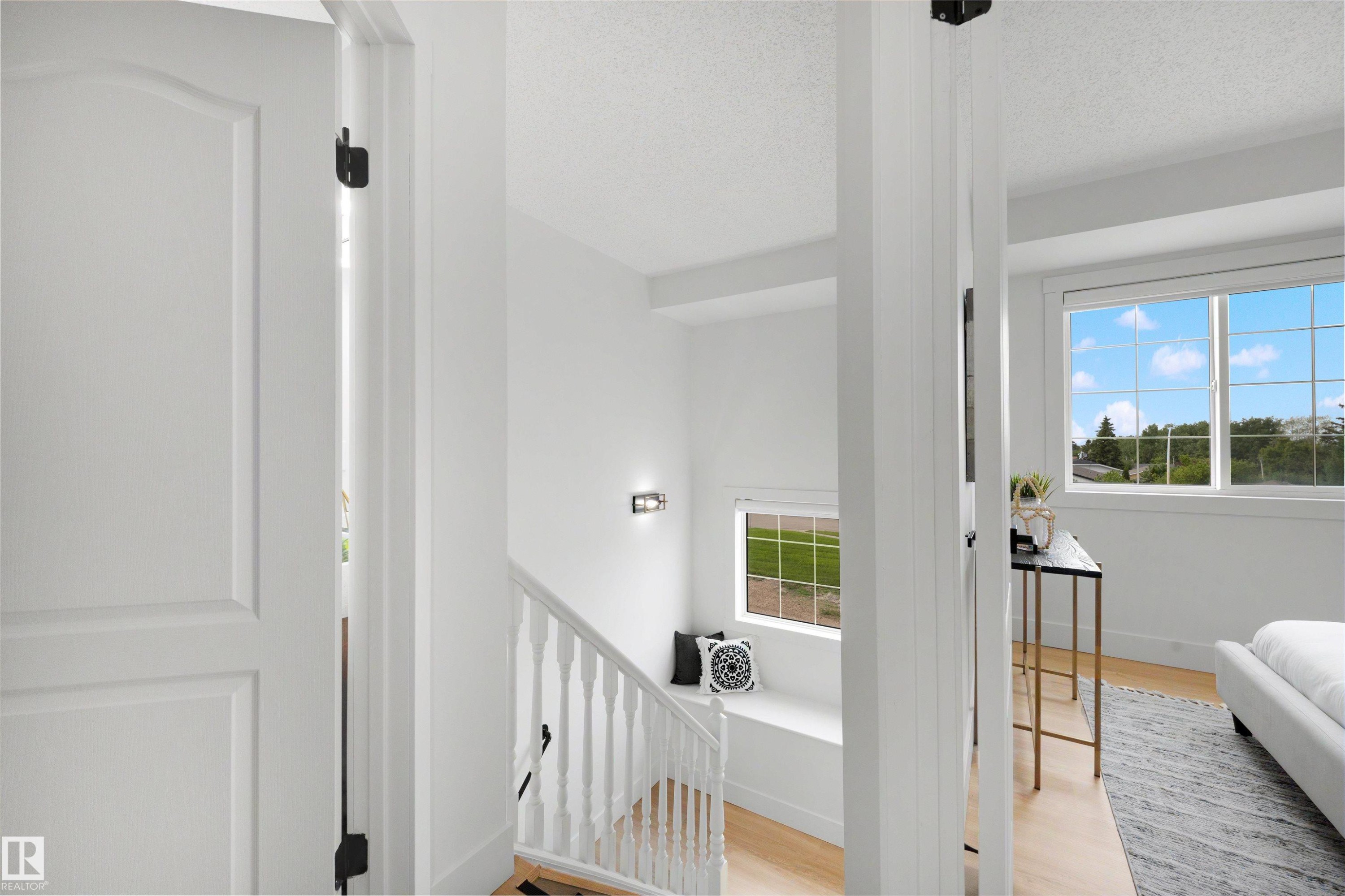 Upper-level landing featuring a white baluster railing and wood-finish flooring - 12611 47 Street, Edmonton, AB