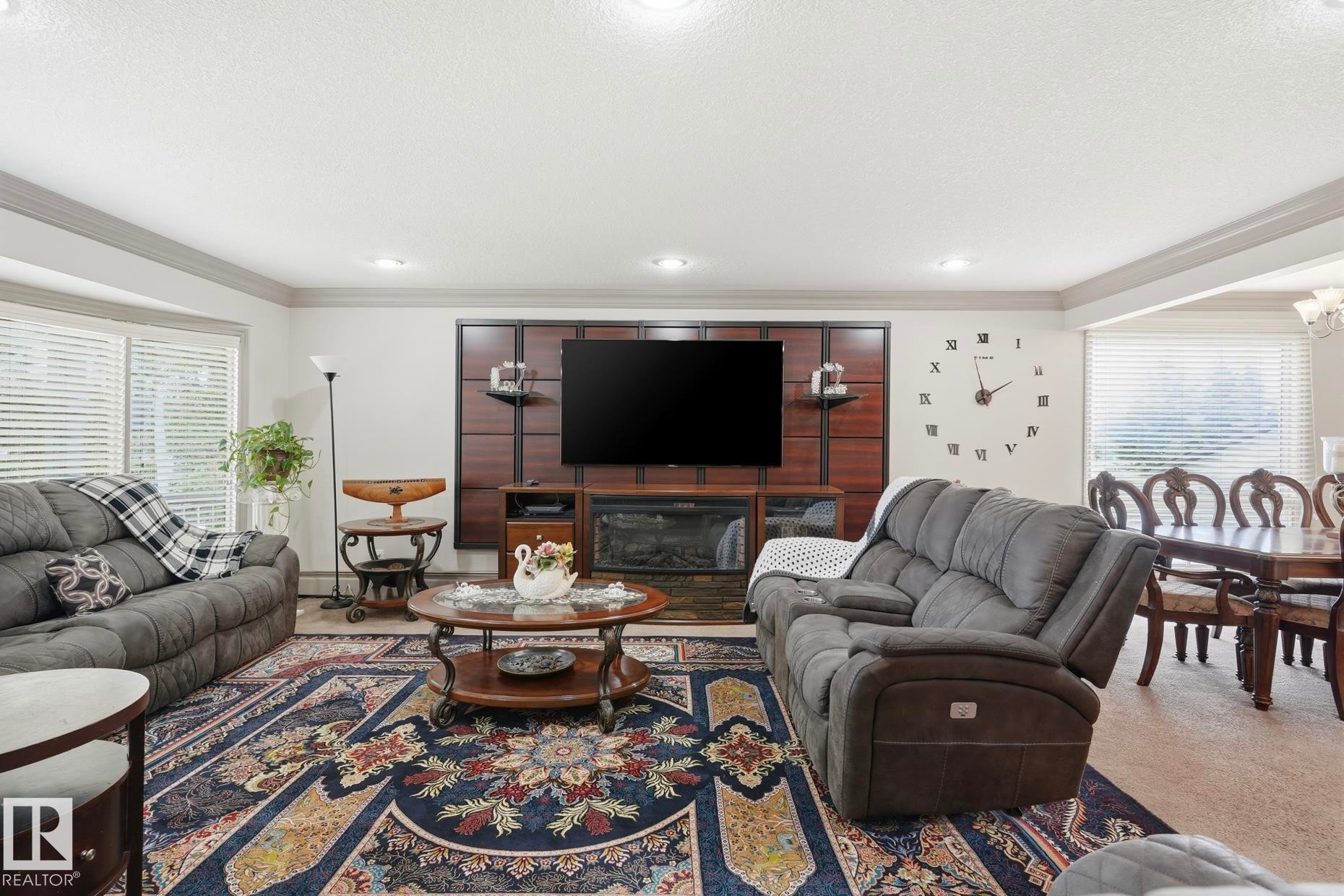 Spacious living area featuring a custom media wall with an integrated fireplace - 12131 101 Street Nw, Edmonton, AB