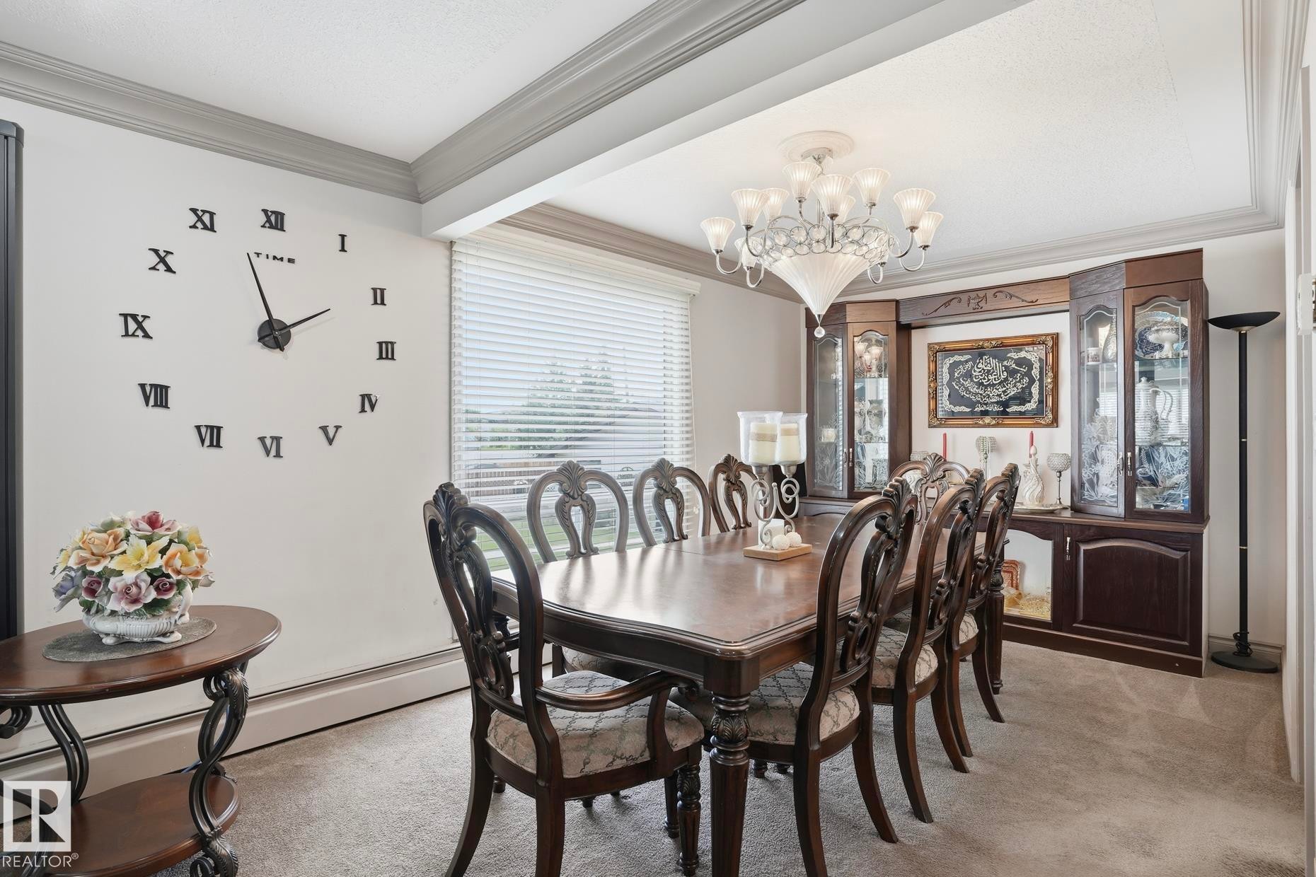 Formal dining space featuring a large chandelier, built-in display cabinetry, a rectangular window with horizontal blinds, and crown molding - 12131 101 Street Nw, Edmonton, AB